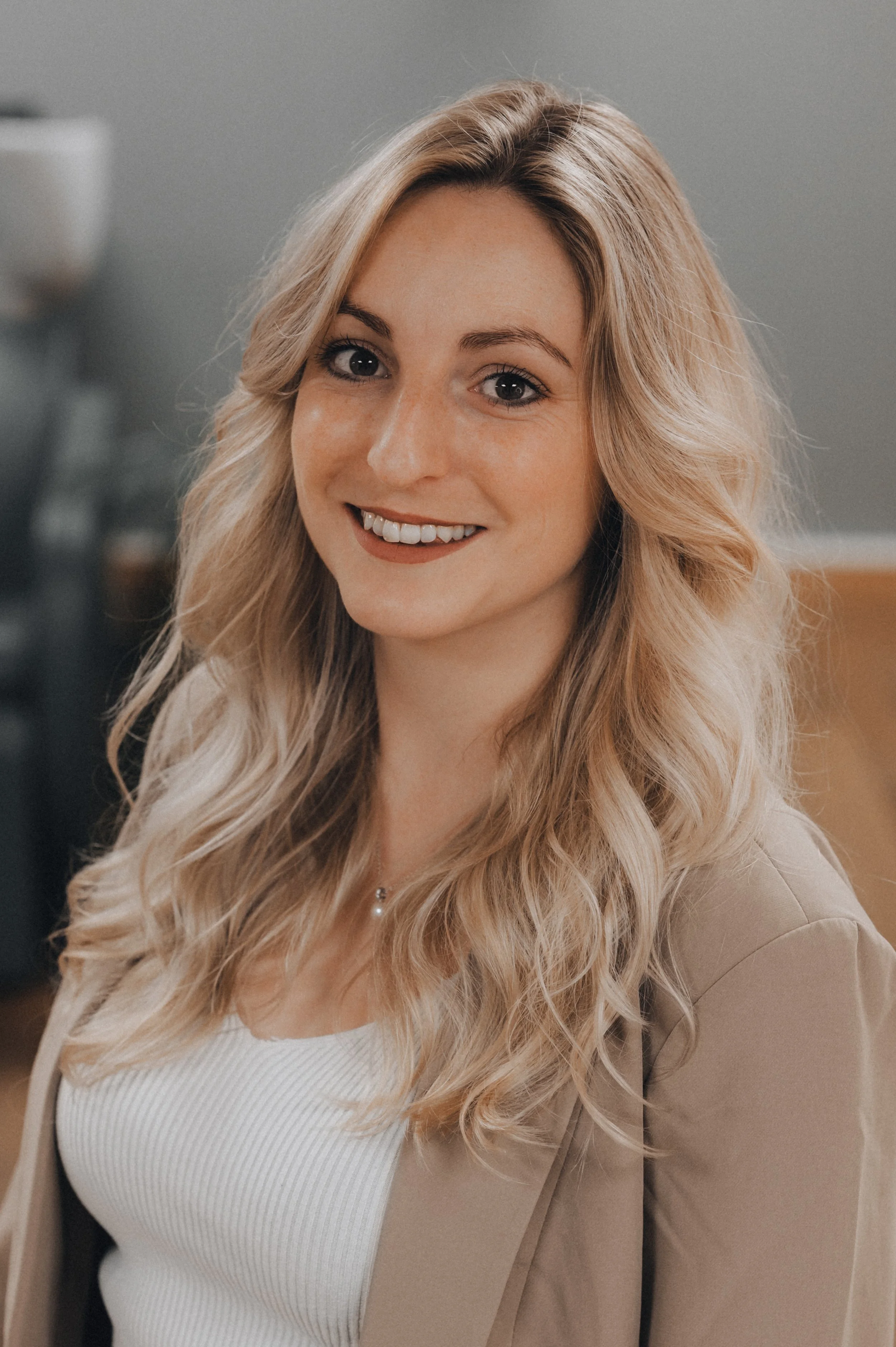 Ein lächelndes junges Frau mit langen, lockigen blonden Haaren, im Büro oder Haushalt setting.