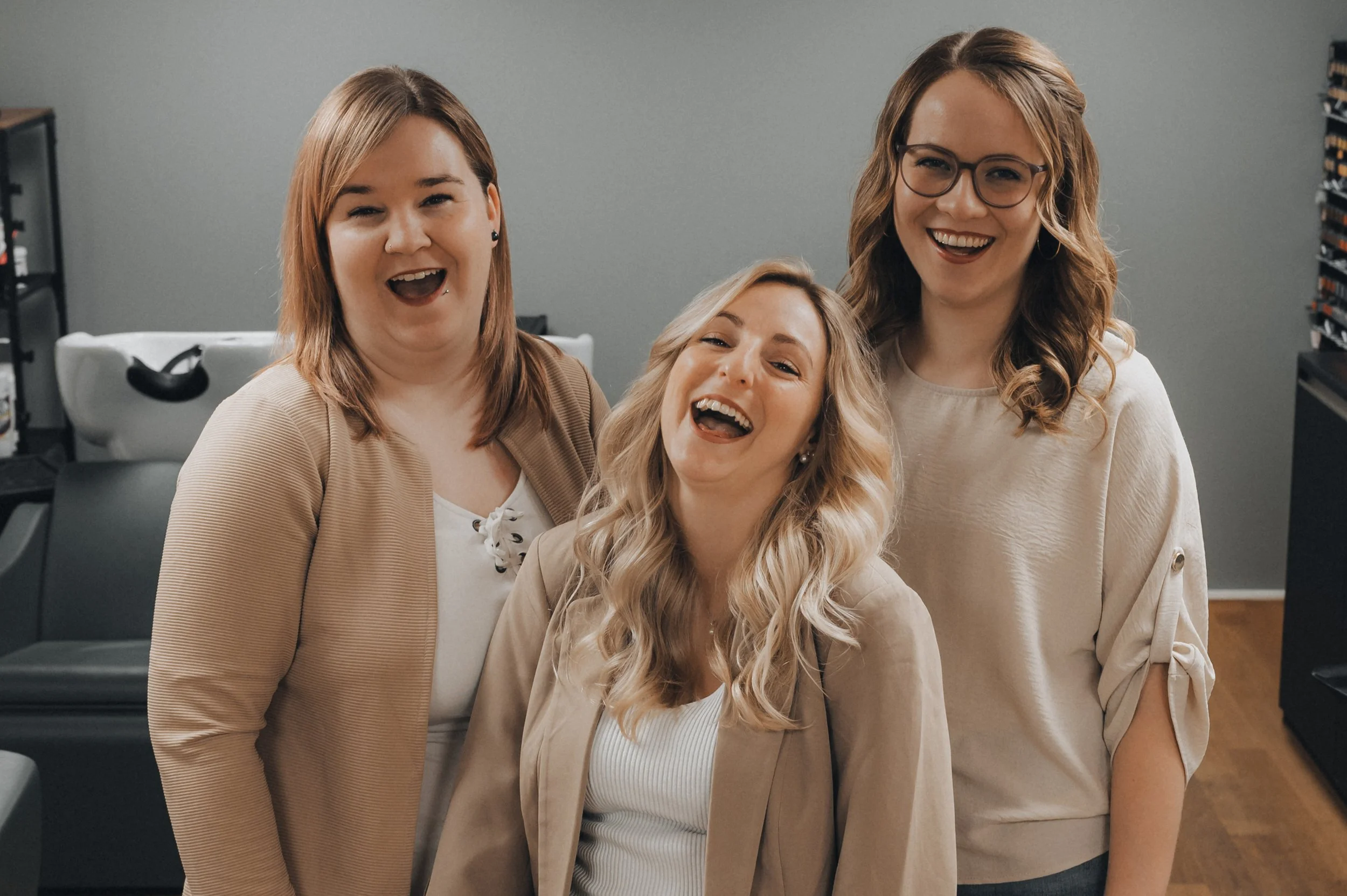 Drei lachende Frauen in einem Büro, die Spaß haben.