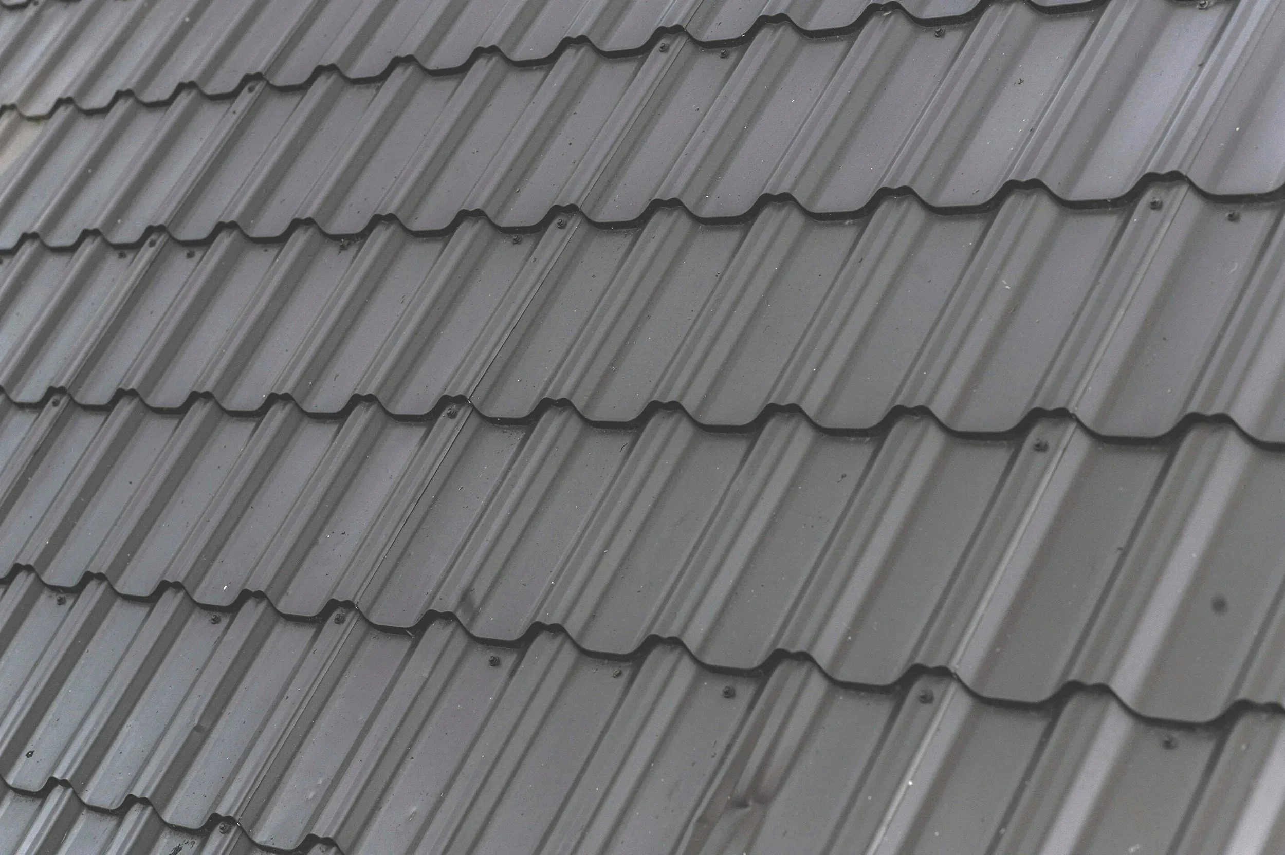 Close-up of gray metal roofing tiles arranged in an overlapping pattern.