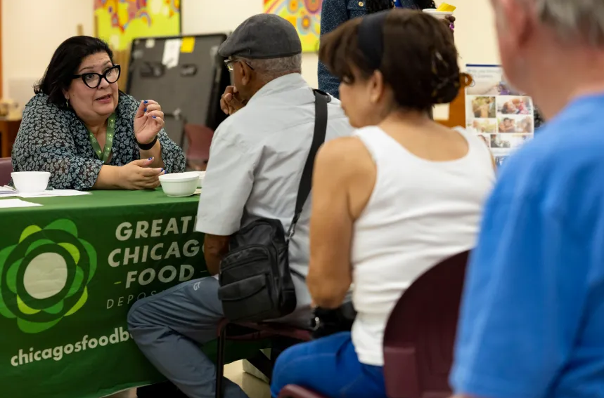 An outreach coordinator for the Food Depository helps a line of people with questions about their SNAP benefits