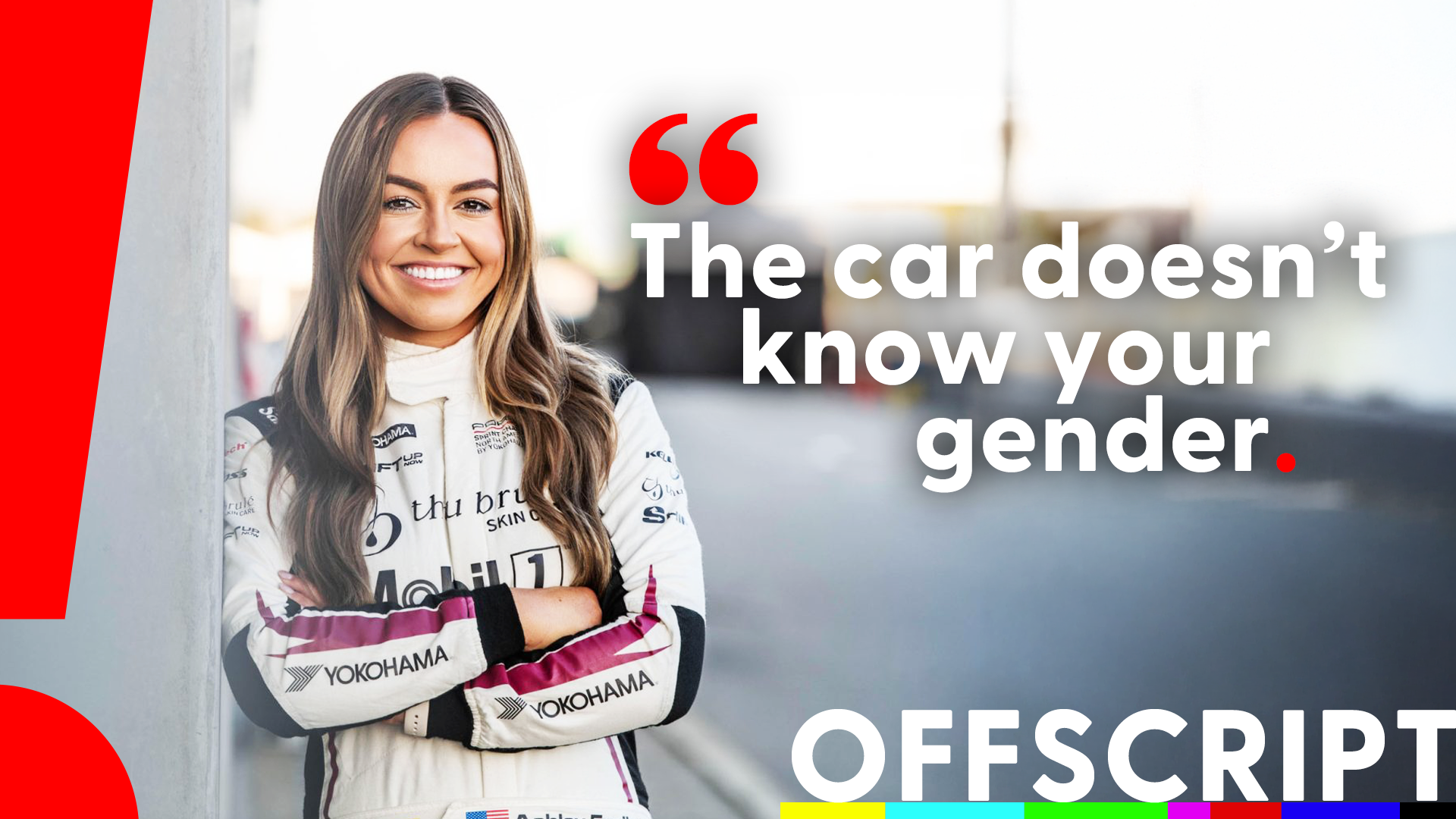 A smiling woman in a racing suit leaning against a wall, with a quote that says, 'The car doesn't know your gender,' on a blurred background with colorful stripes at the bottom.