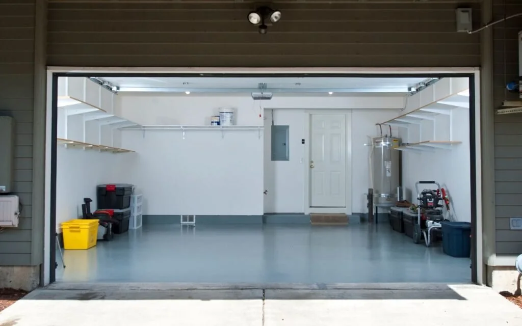 Clean, organized garage with shelves, storage bins, a workbench, and a water heater.