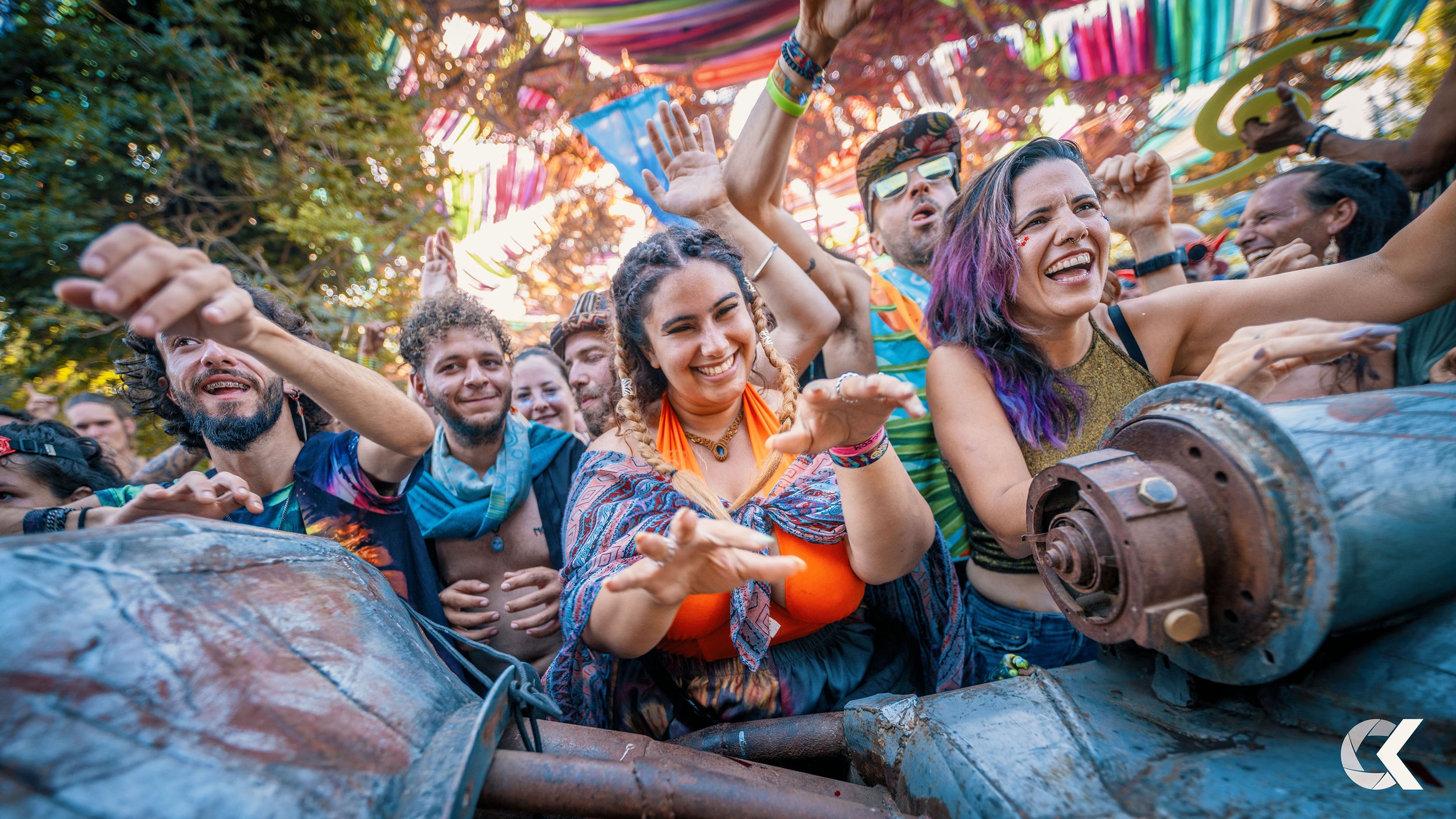 A group of people at a festival or outdoor event, dancing and enjoying themselves under colorful decorations.