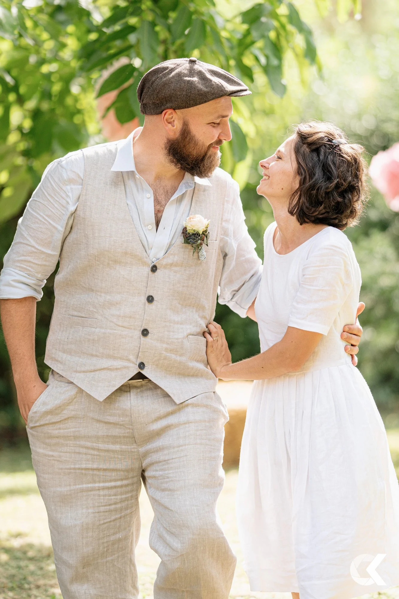 A couple in wedding attire sharing an intimate moment outdoors, surrounded by greenery.