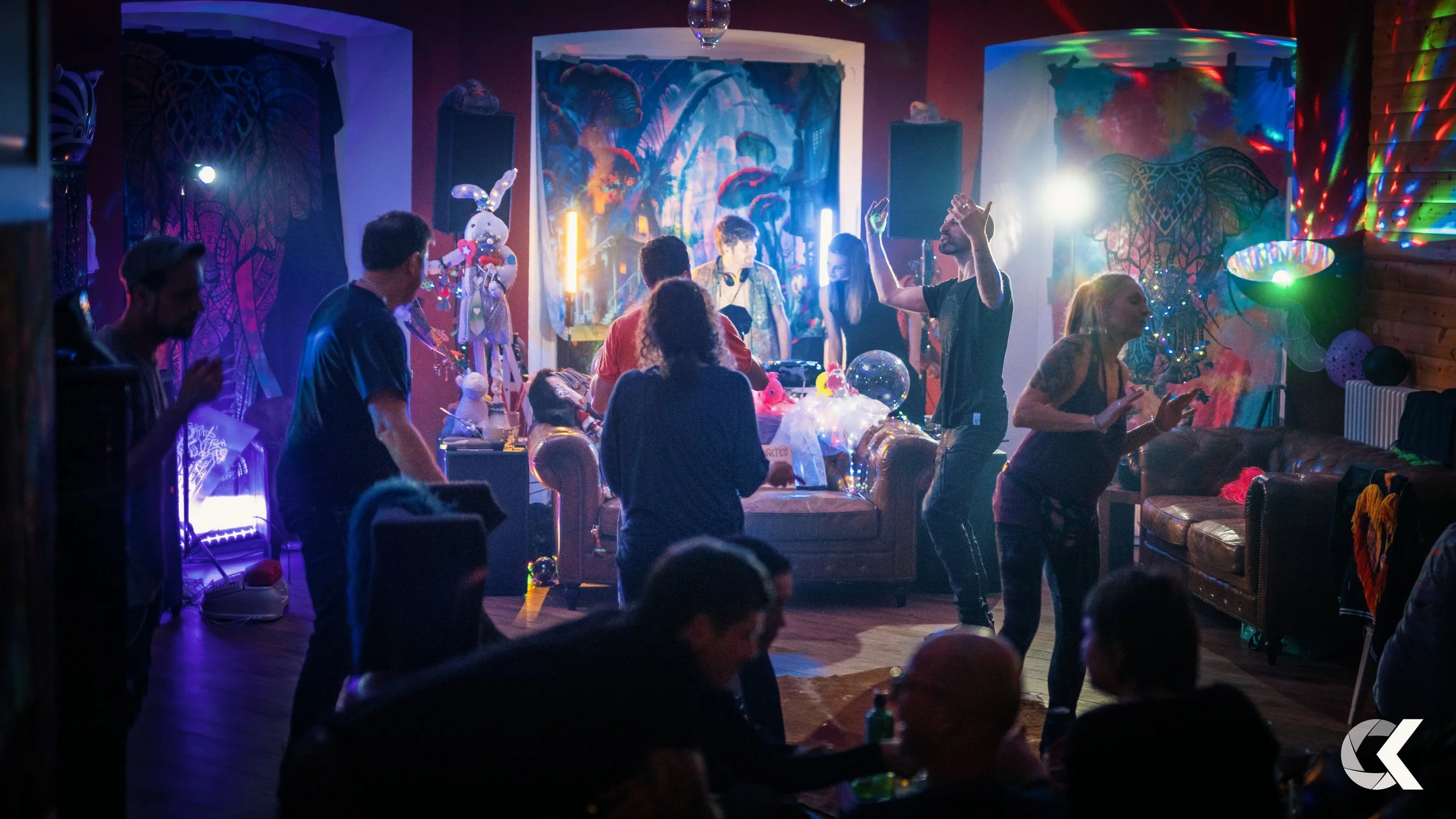 People dancing and socializing at a lively birthday party with colorful decorations, balloons, and disco lights.