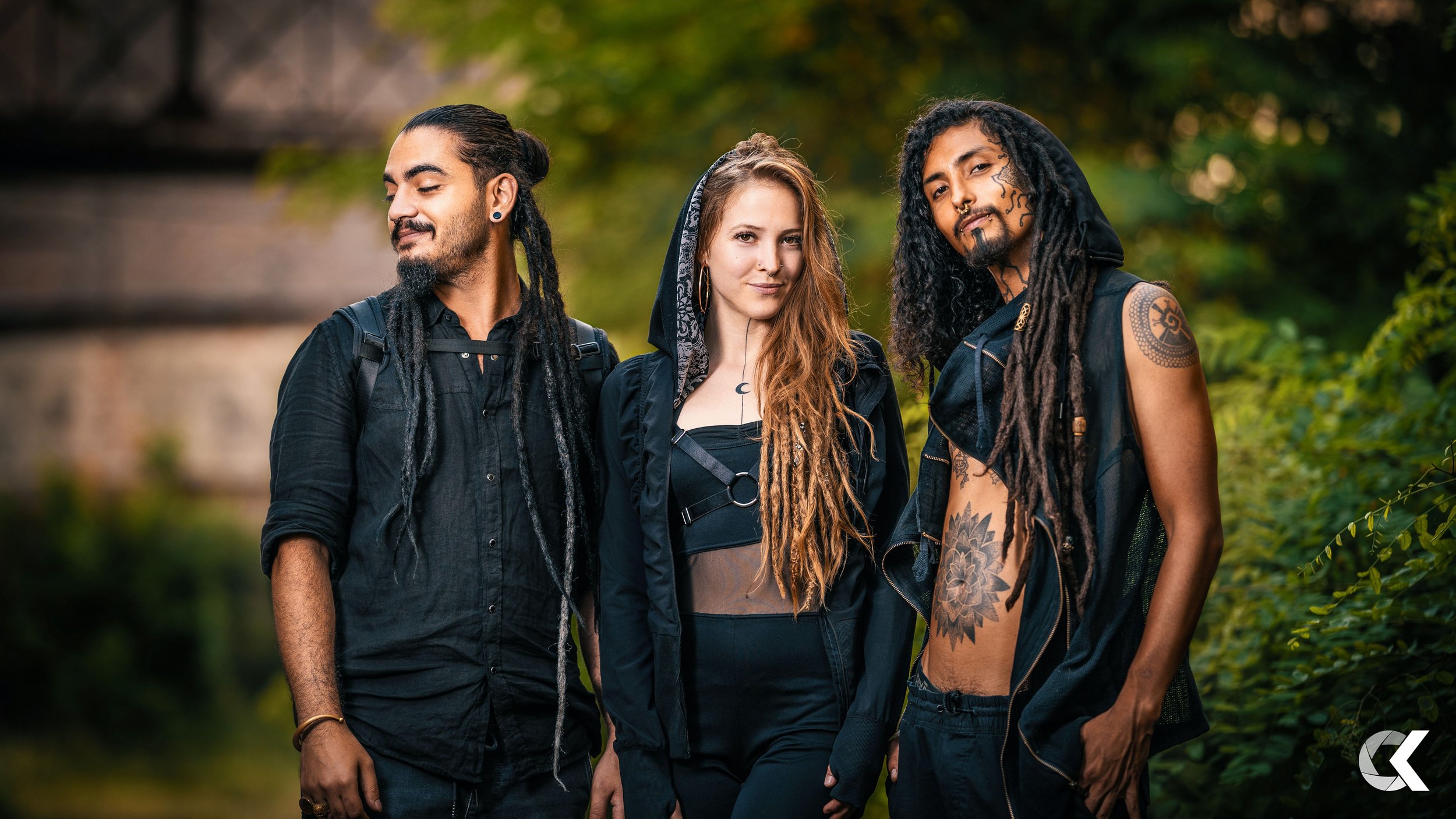 Three diverse young adults standing outdoors in a lush, green environment, looking confident and stylish.