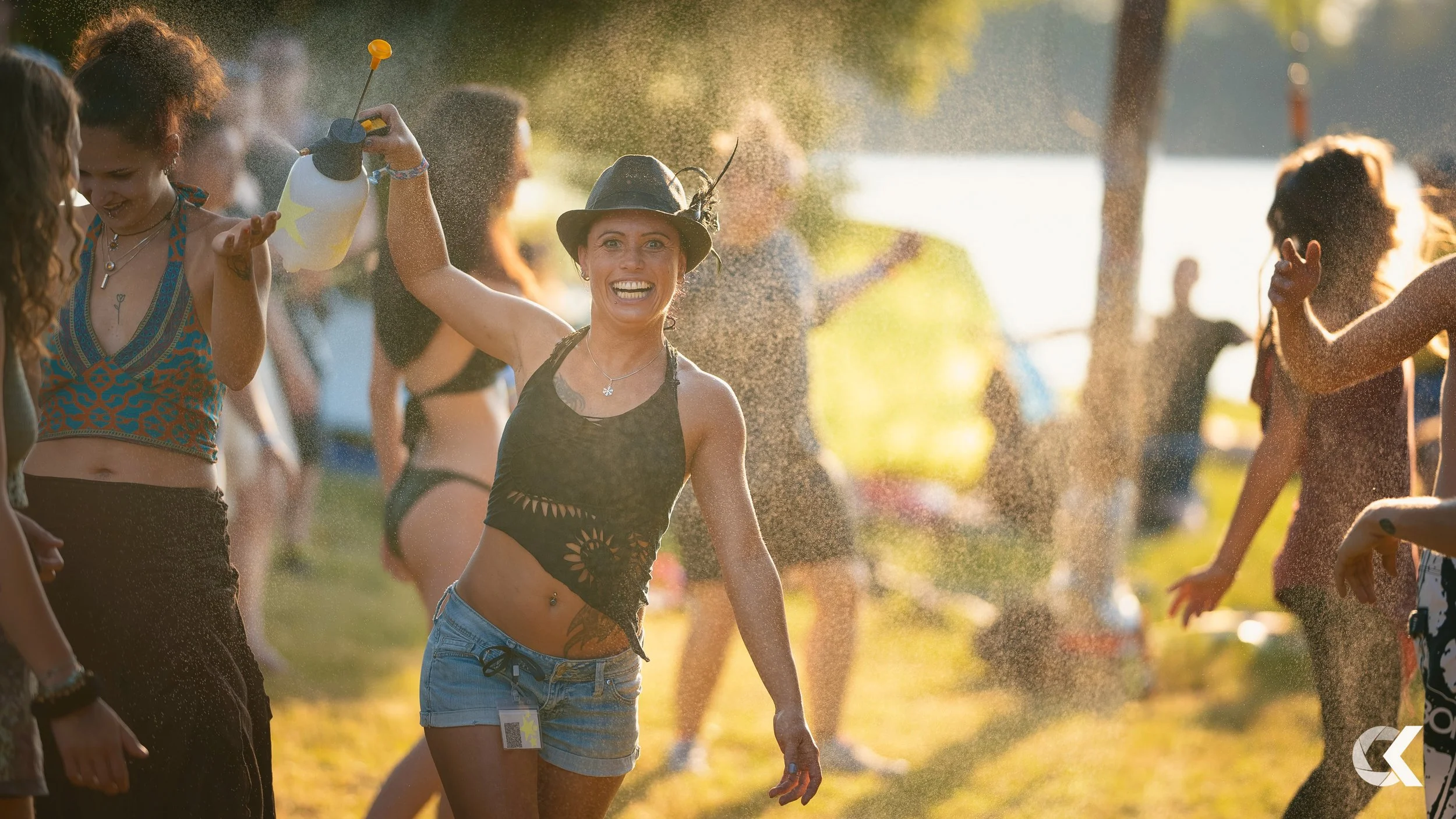 People at an outdoor party playing with water on a sunny day, with smiling faces and summer clothing.