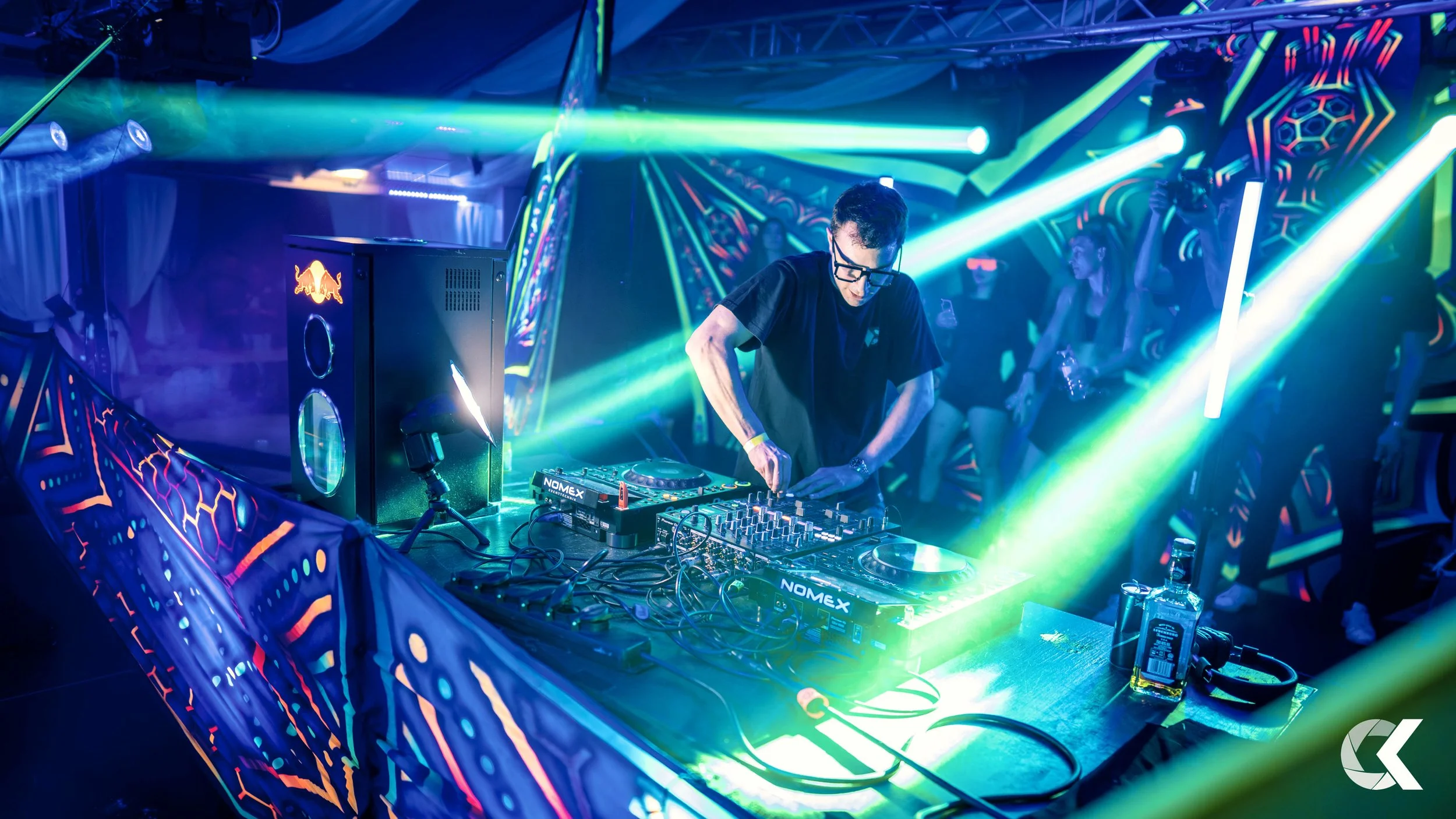 DJ performing at a nightclub with colorful lights and a techno crowd in the background.