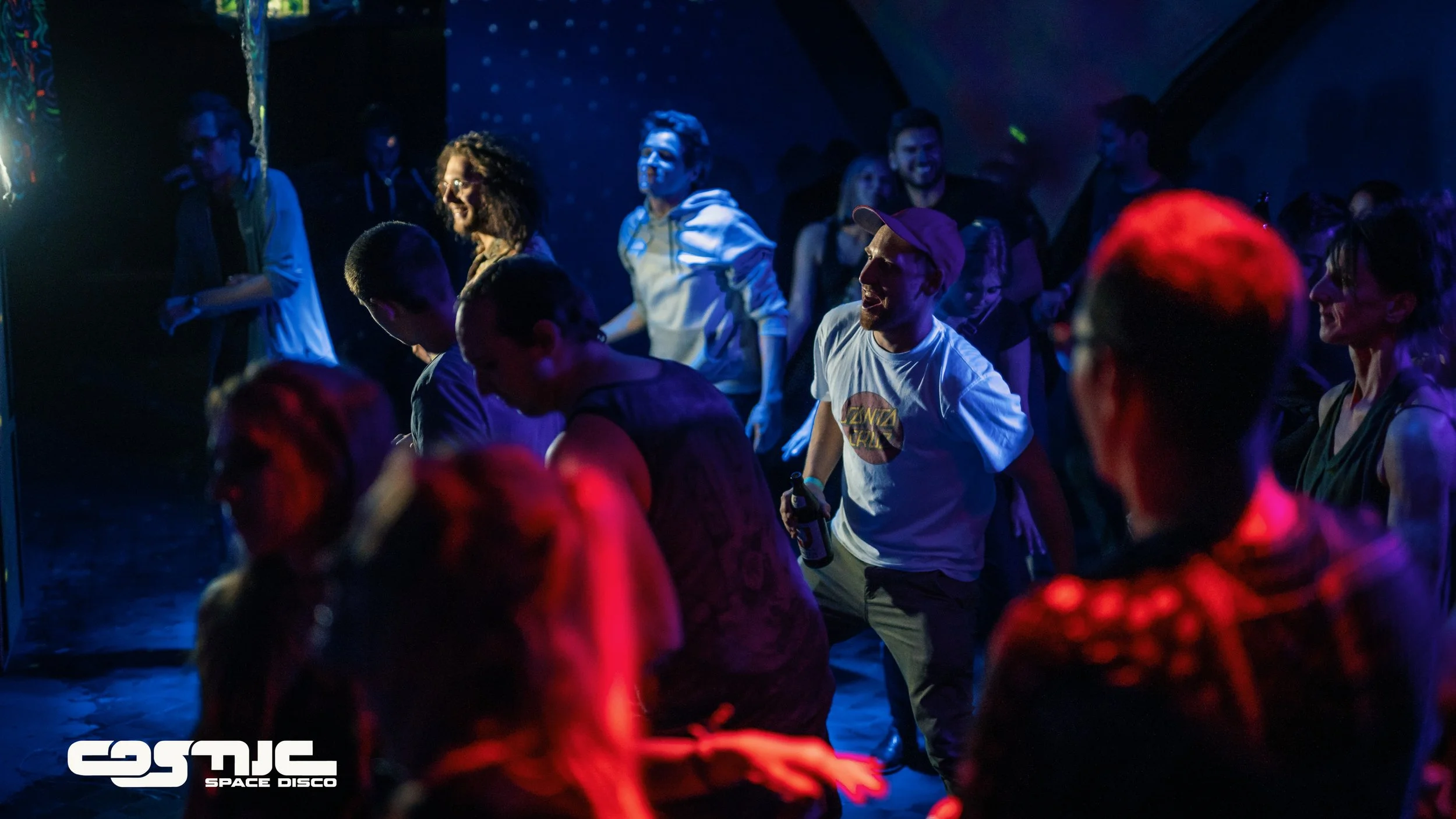 People dancing at a space-themed disco club with colorful lighting and the 