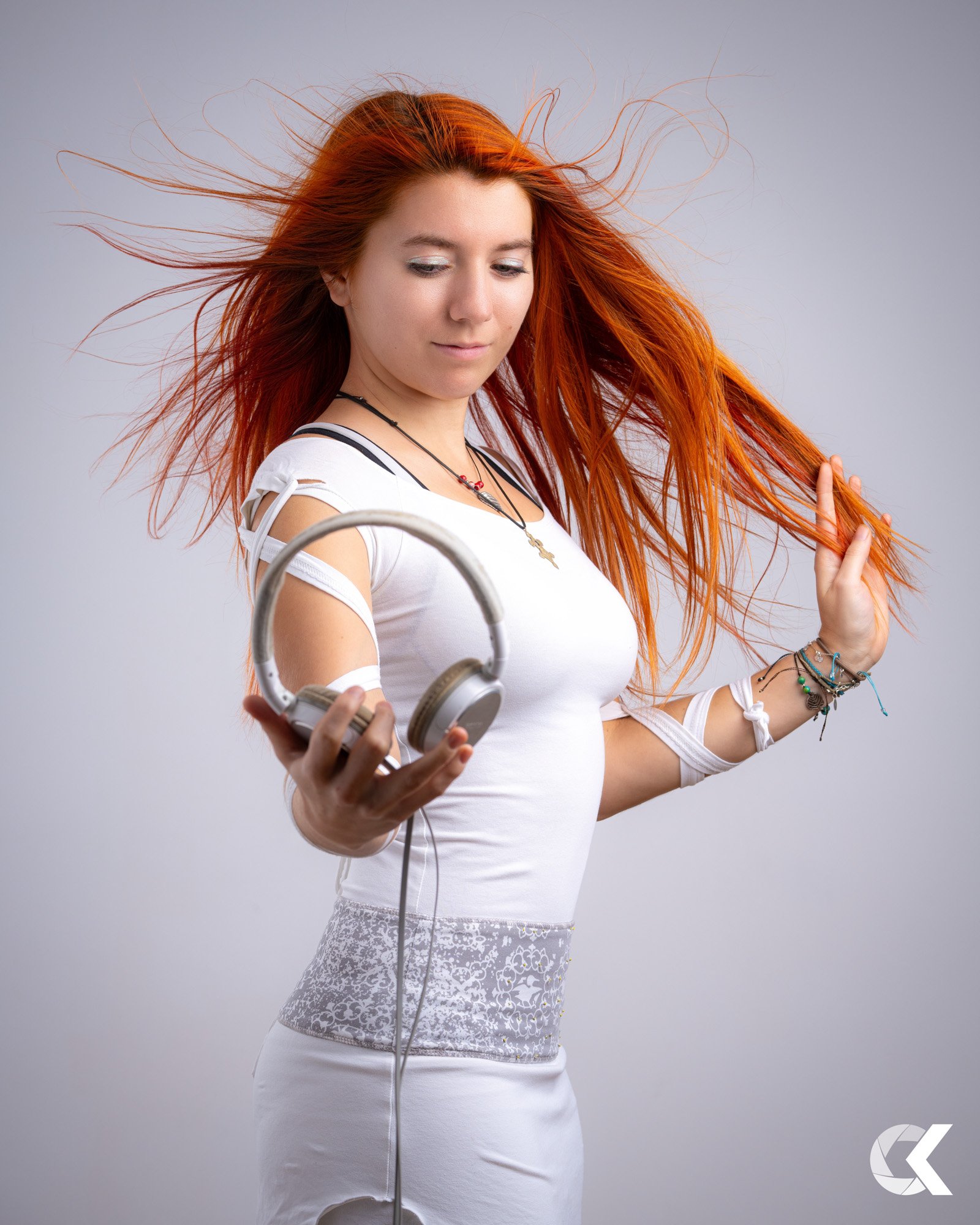 Junge Frau mit roten Haaren, die Kopfhörer hält, während sie tanzt.