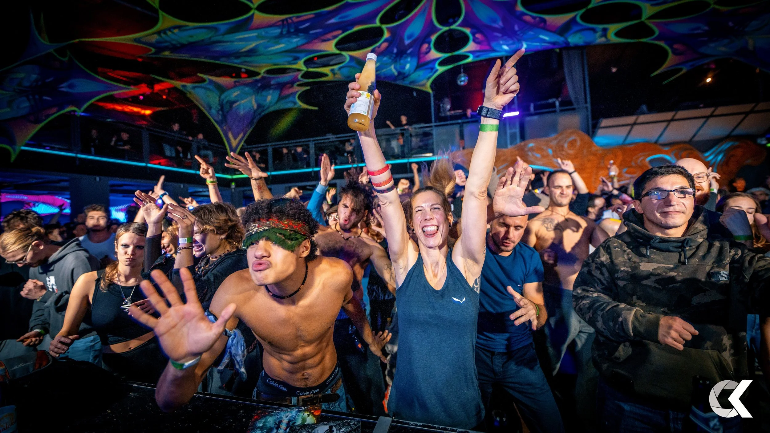 Crowd dancing and enjoying music at a nightclub, with colorful lighting and ceiling decorations.