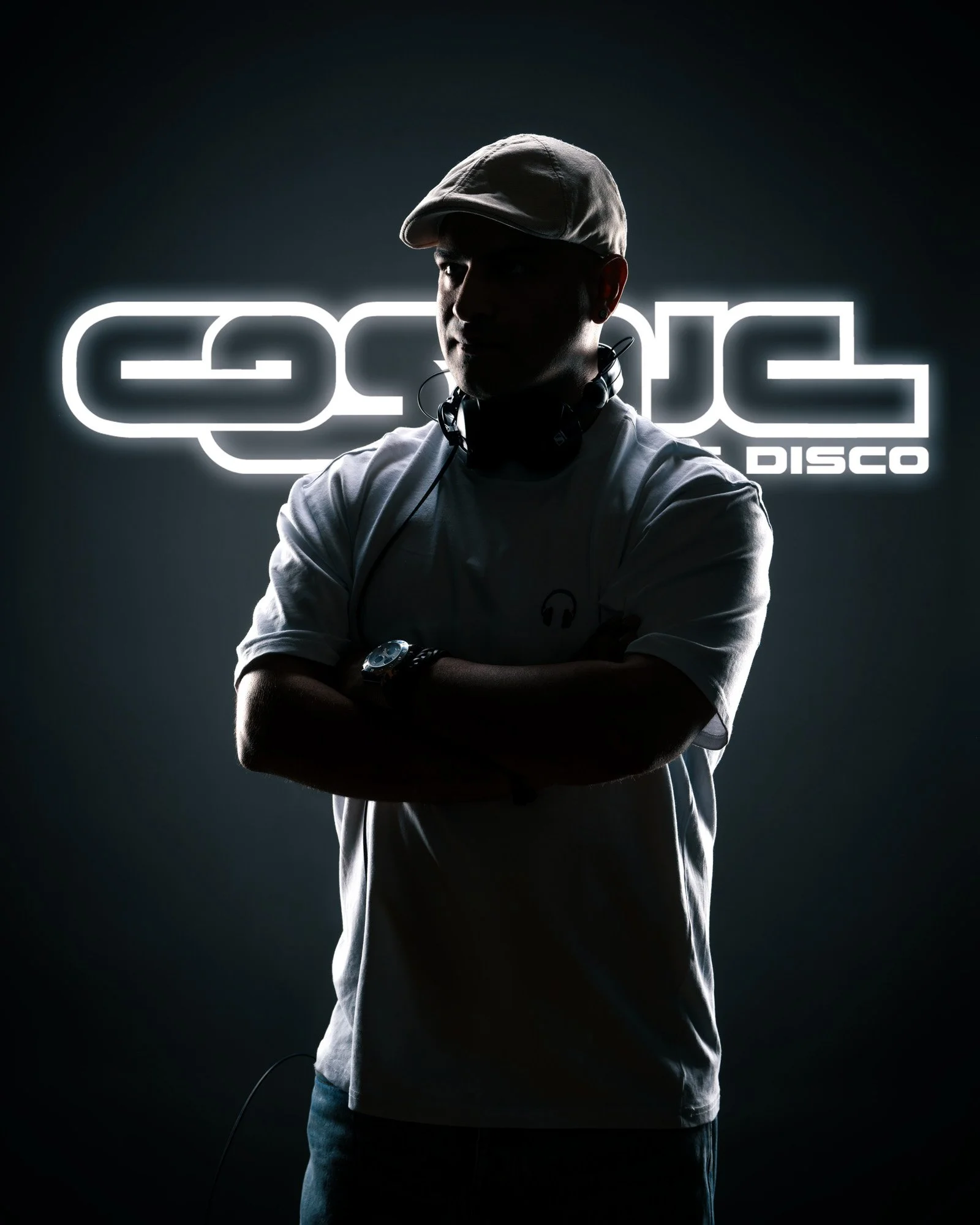A silhouette of a man wearing a cap and headphones, crossing his arms, standing in front of a neon sign that reads 'GROOVE DISCO'.