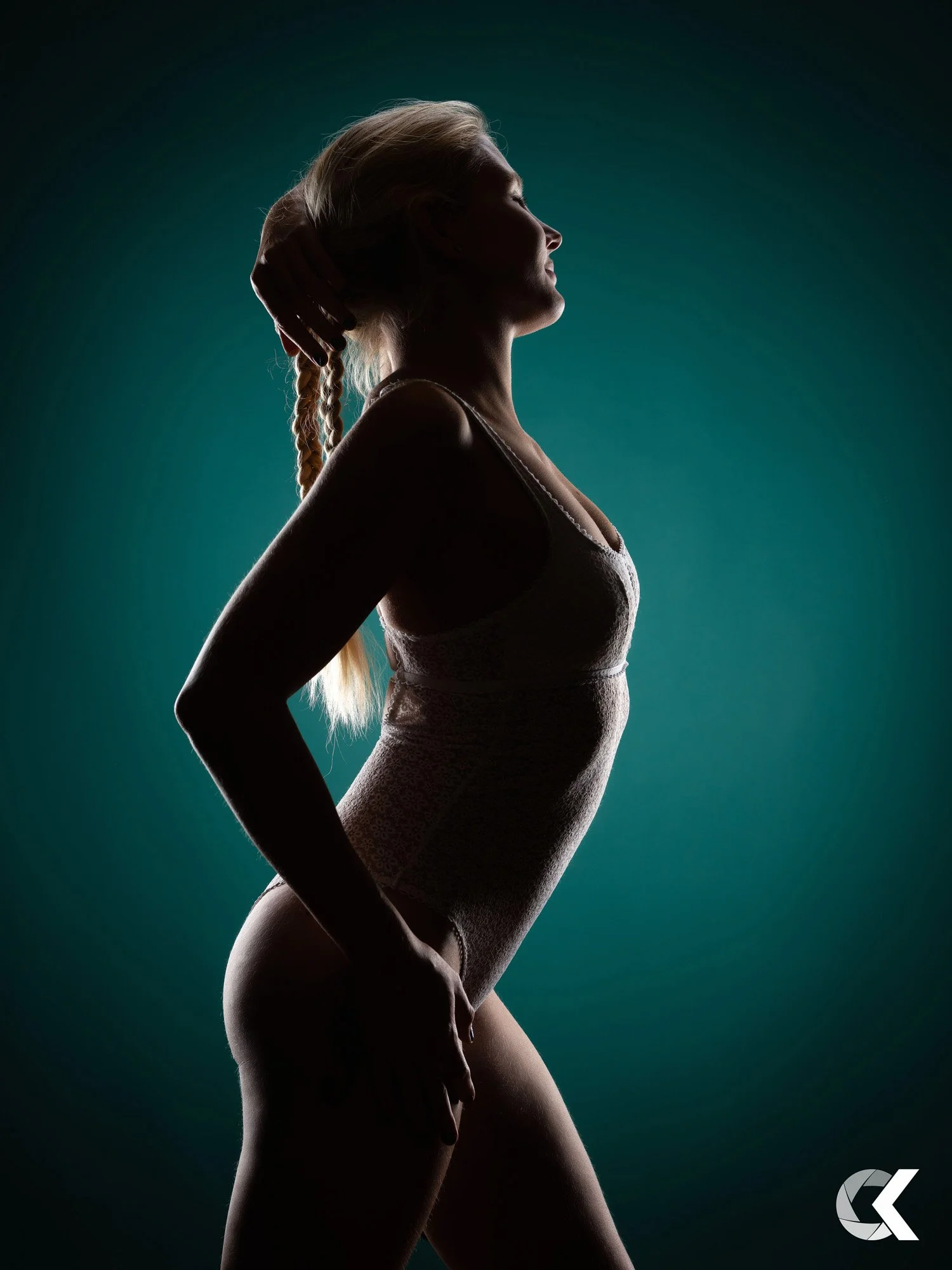 Silhouette einer Frau mit lockigem Haar, die eine Hand im Haar hält und den Kopf leicht nach hinten neigt, vor einem dunklen Hintergrund.