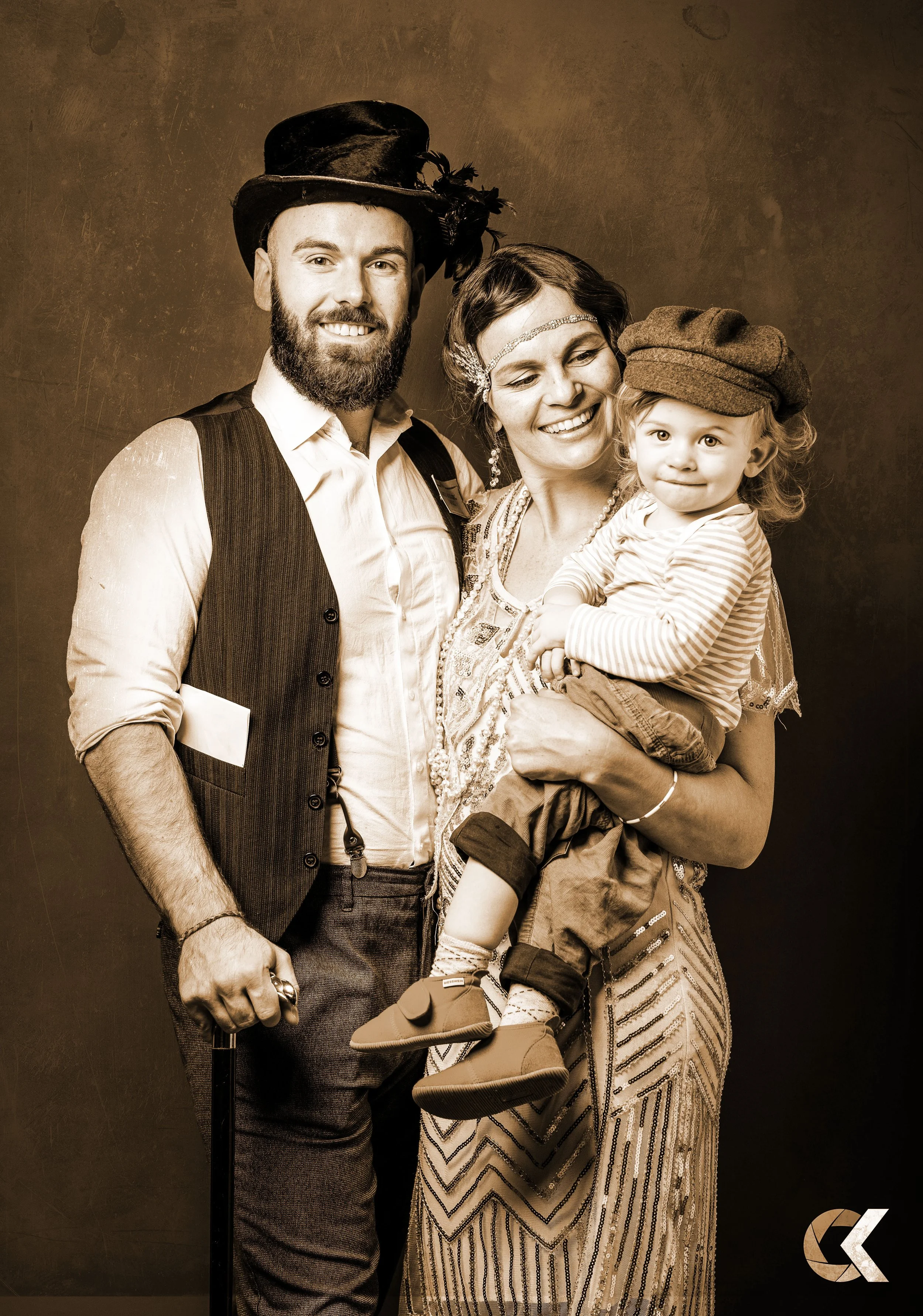 A family dressed in vintage clothing smiling together in sepia tone photo.