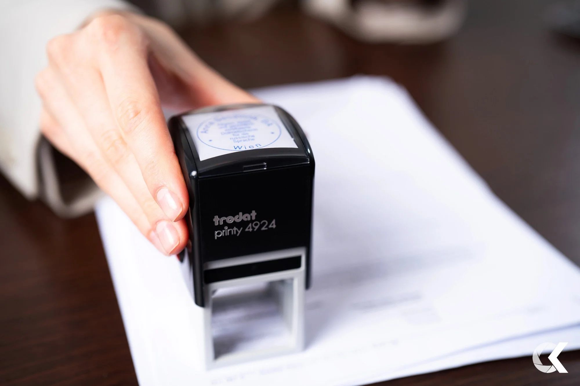 Person stamping paper with a Trodat Printy 4924 rubber stamp on white paper.