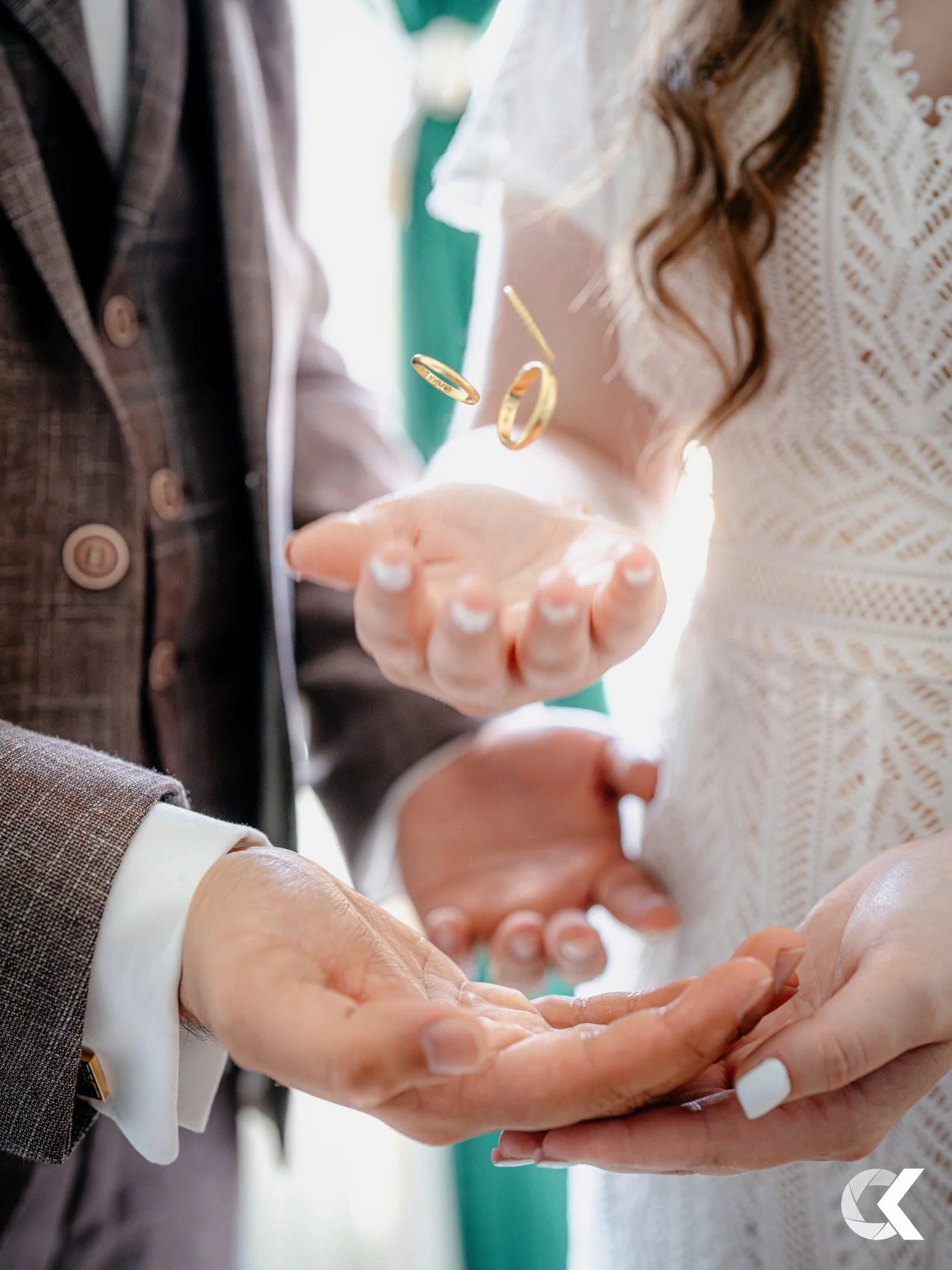 Close-up of a couple exchanging wedding rings during a wedding ceremony, with the bride holding her hand over the groom's hand.