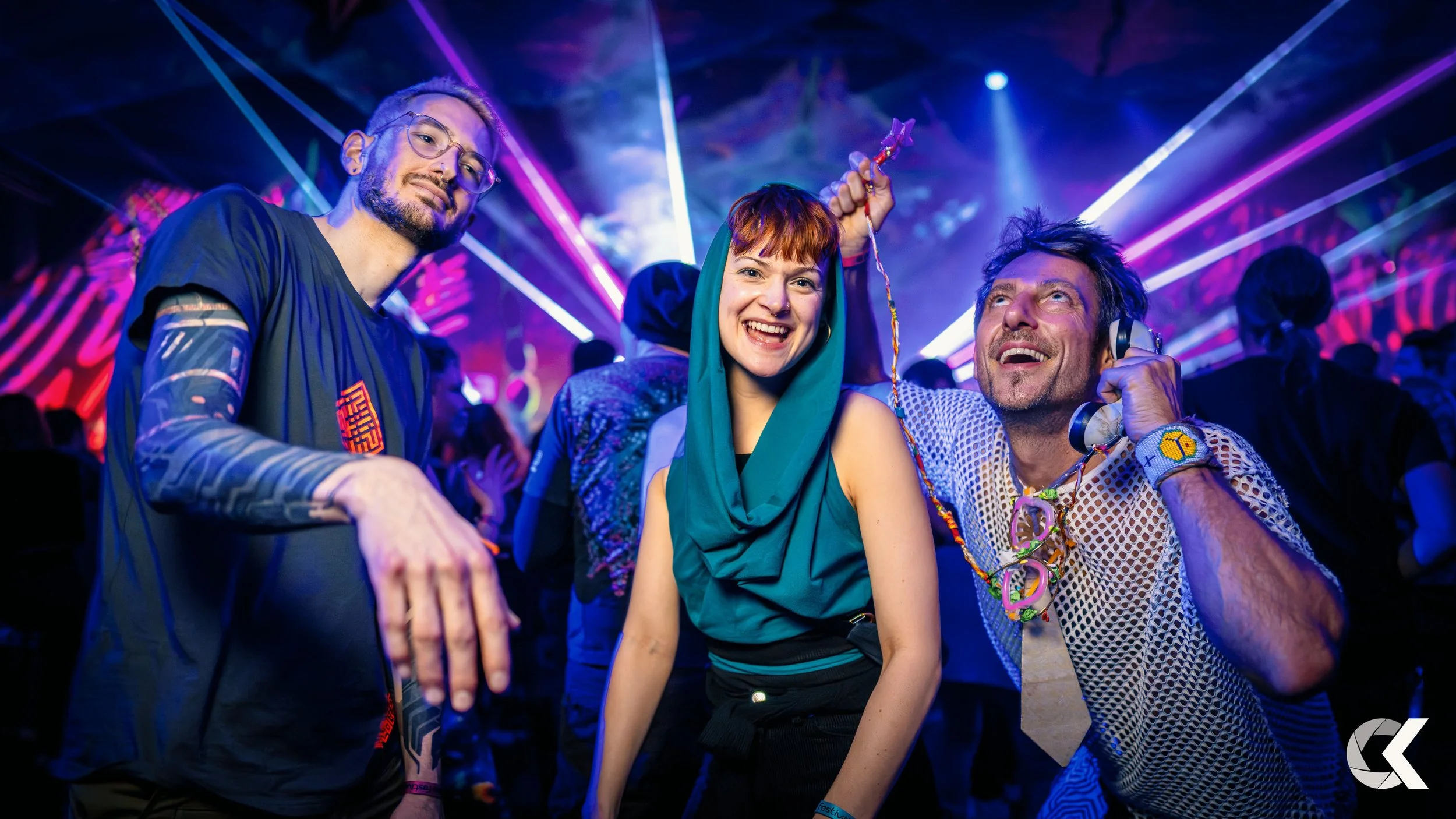 People dancing and enjoying themselves at a nightclub with colorful laser lights and a lively atmosphere.