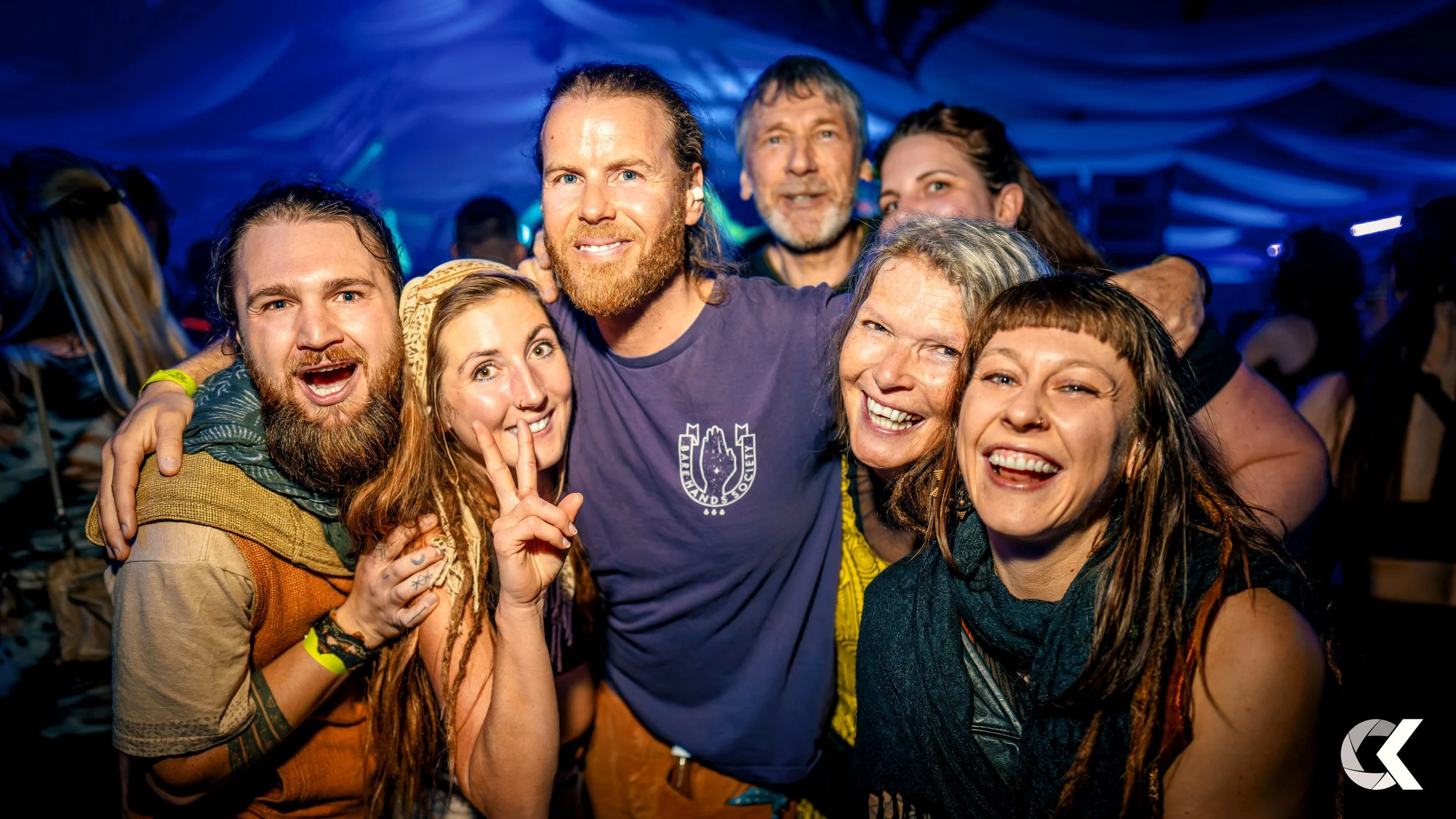 Group of six people at a party, smiling and celebrating, with a dark blue and purple background.