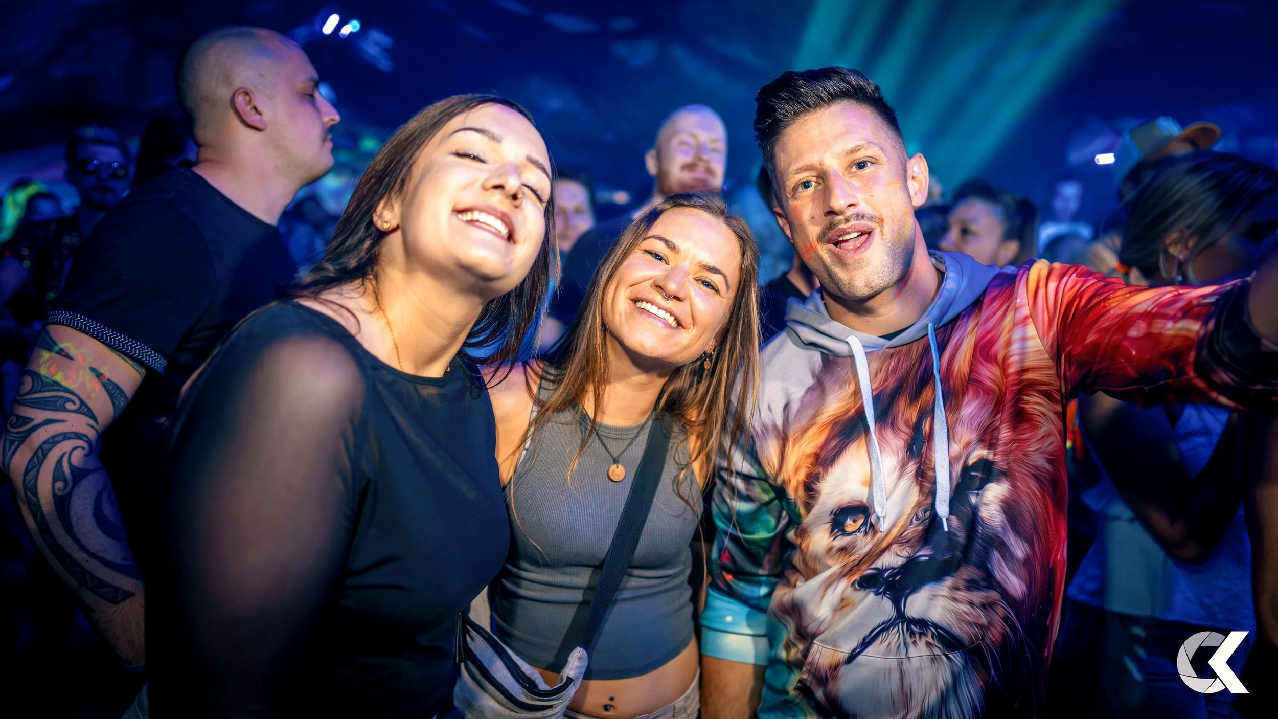 People enjoying themselves at a crowded party or concert with colorful lighting.