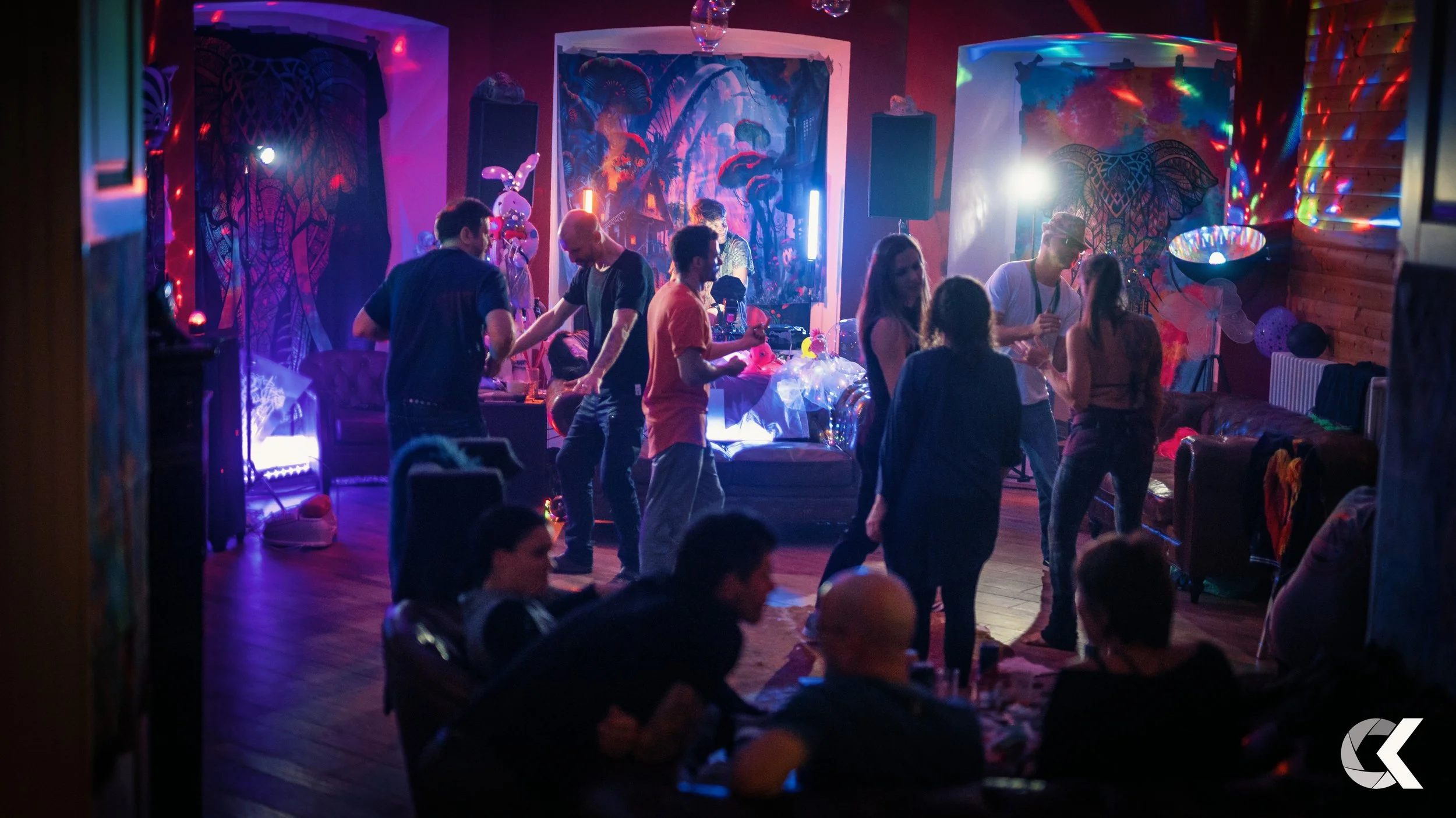 People dancing and socializing at a party with colorful lighting and decorations.