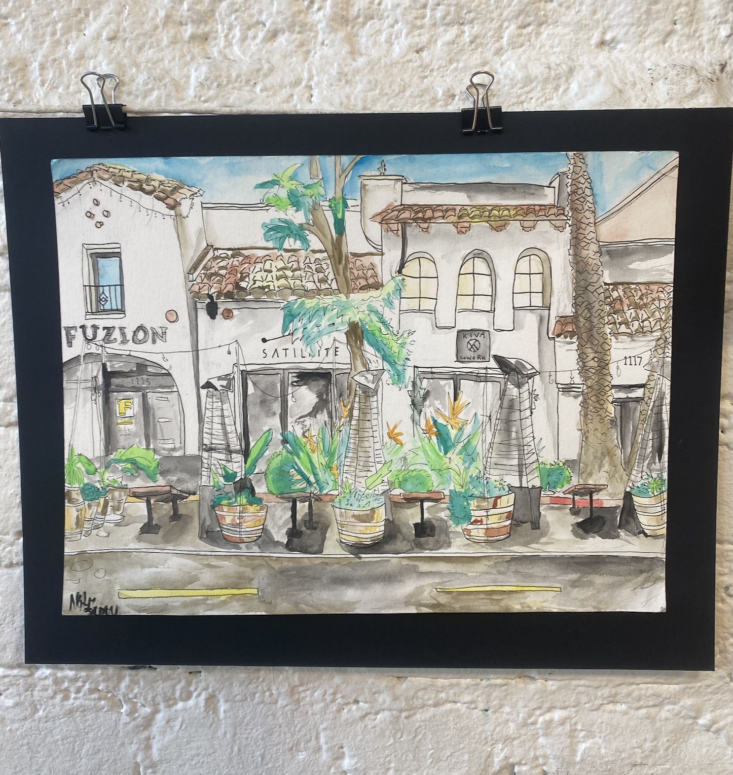 A watercolor painting of a courtyard scene featuring buildings with tiled roofs, potted plants, and trees, with signs reading 'Fuzion' and 'Satellite'.