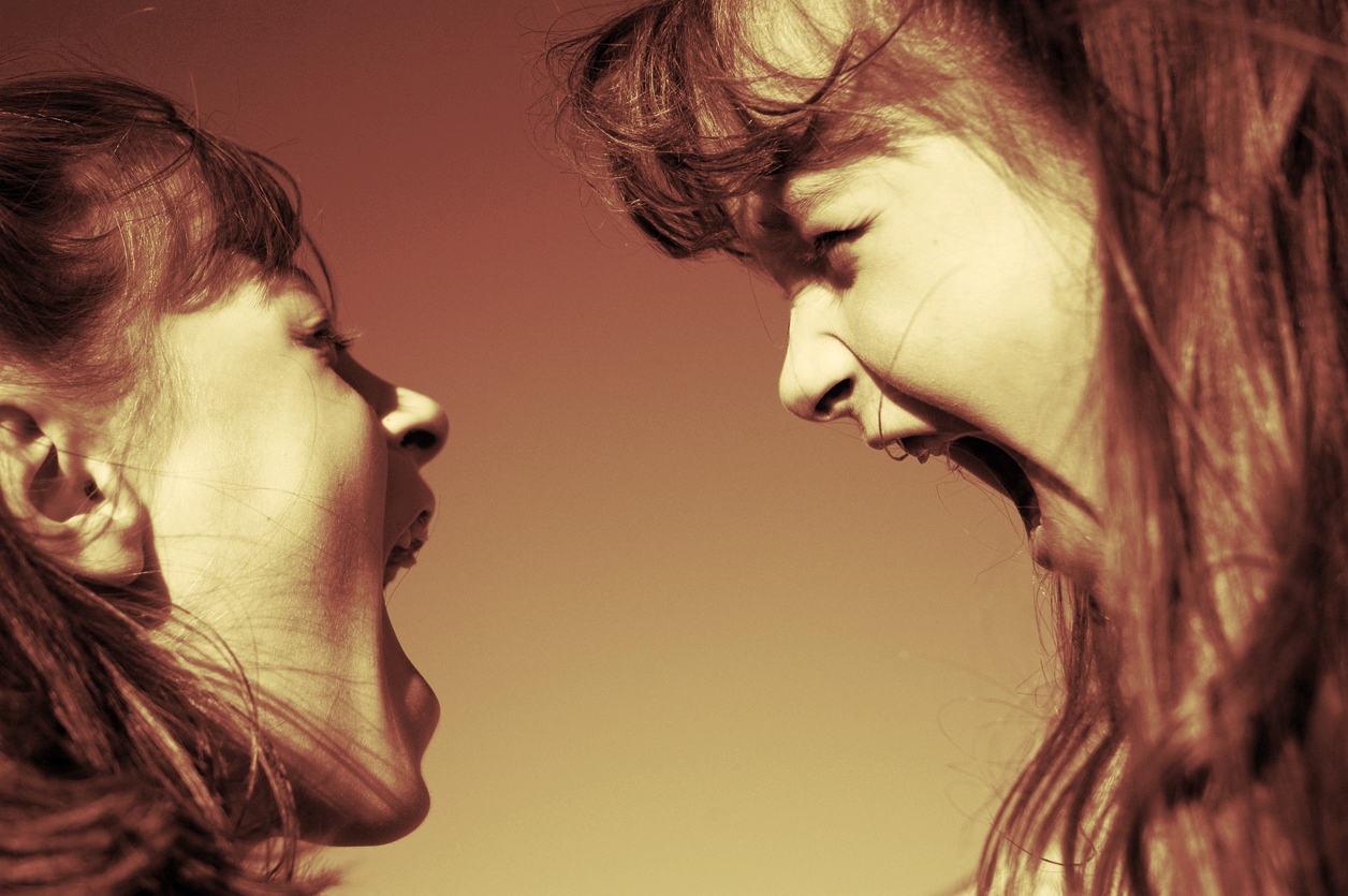 Two women facing each other with mouths open as if shouting or arguing, with intense expressions.
