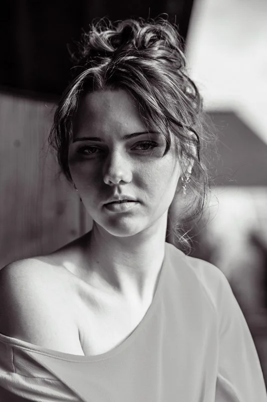 Portrait en noir et blanc d'une femme avec des cheveux bouclés, portant un vêtement léger, regardant sérieusement vers l'objectif.
