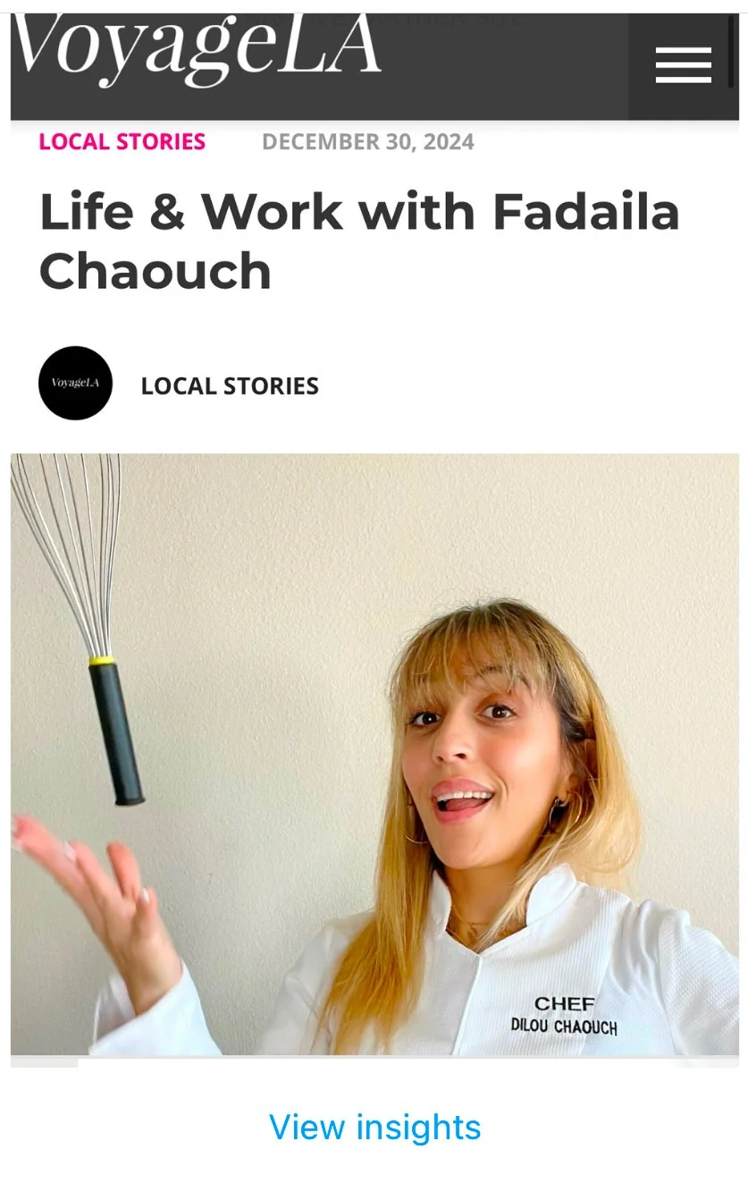 A woman with blonde hair, wearing a chef's coat that says "Chef Dilou Chaouch," is smiling and tossing a whisk into the air against a plain wall background.