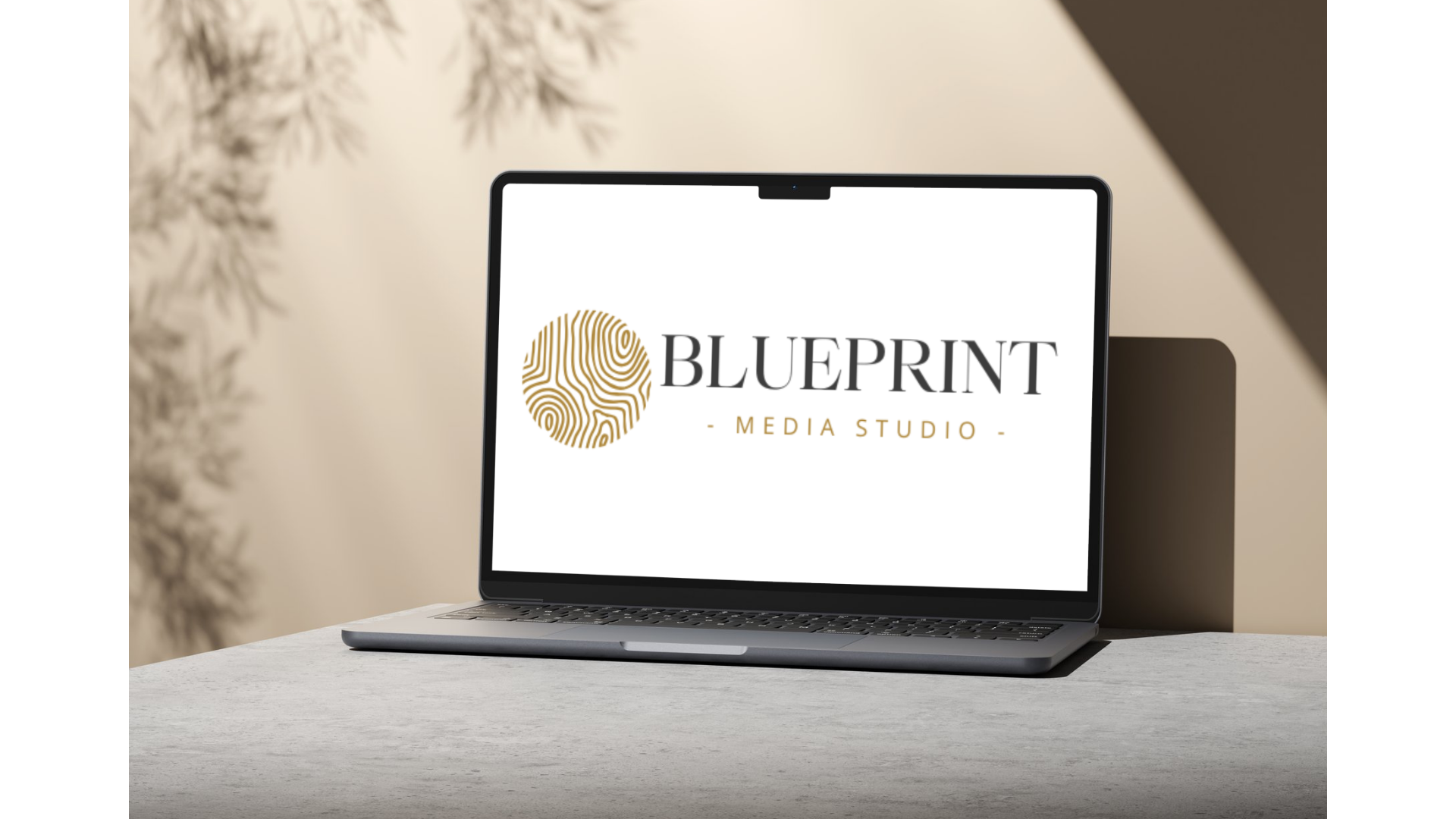 A laptop on a table displaying the logo of Blueprint Media Studio, which features a gold fingerprint circle and the studio's name in black and gold text.