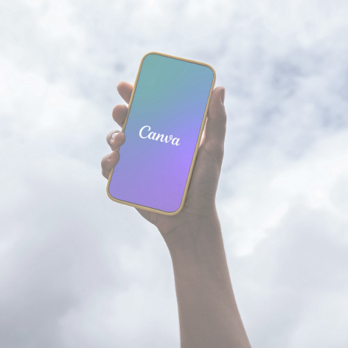 A person holding a smartphone with a Canva logo on the screen, against a cloudy sky background.