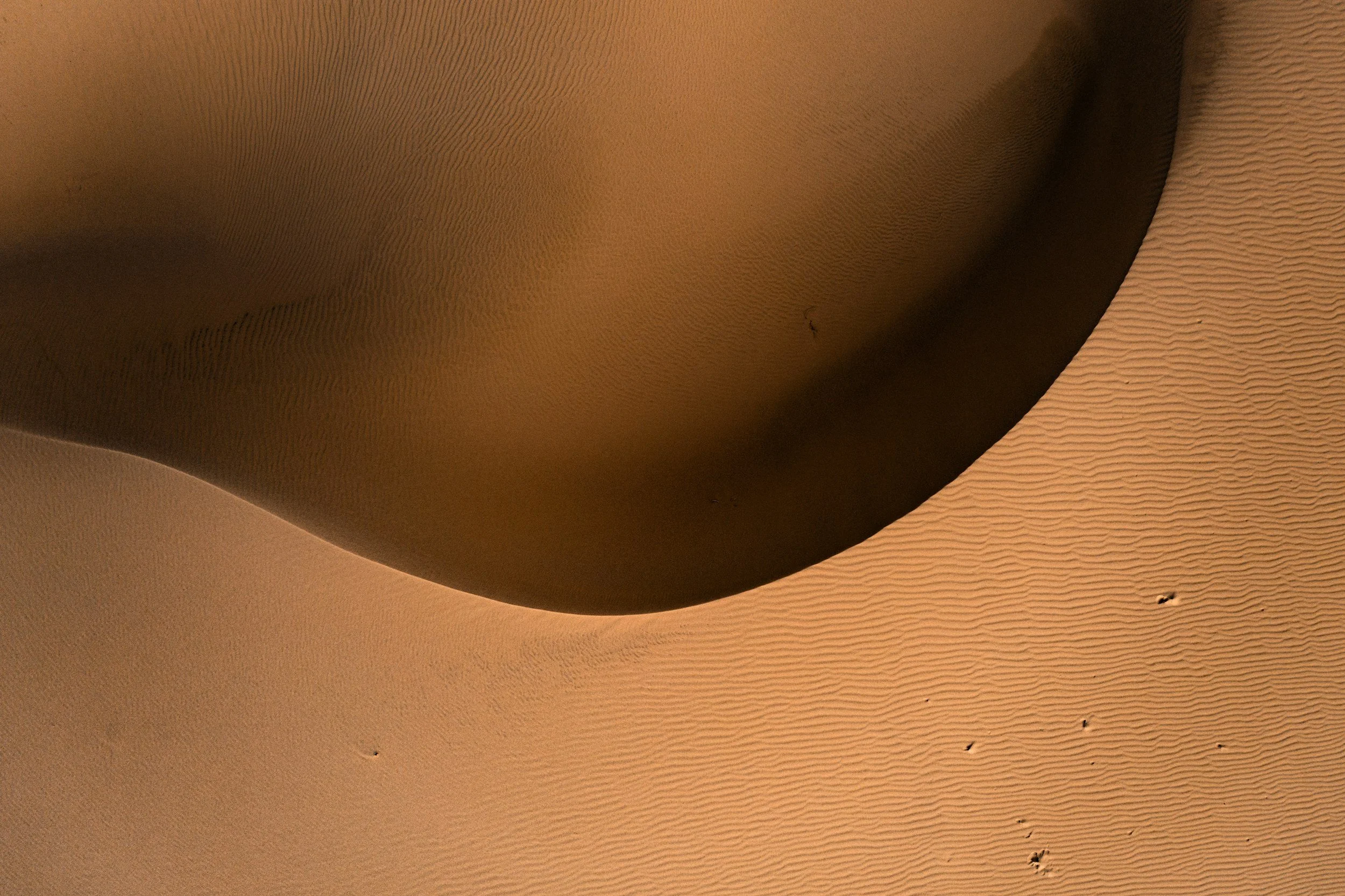 Vista aérea de dunas de arena en un desierto con huellas en la arena.