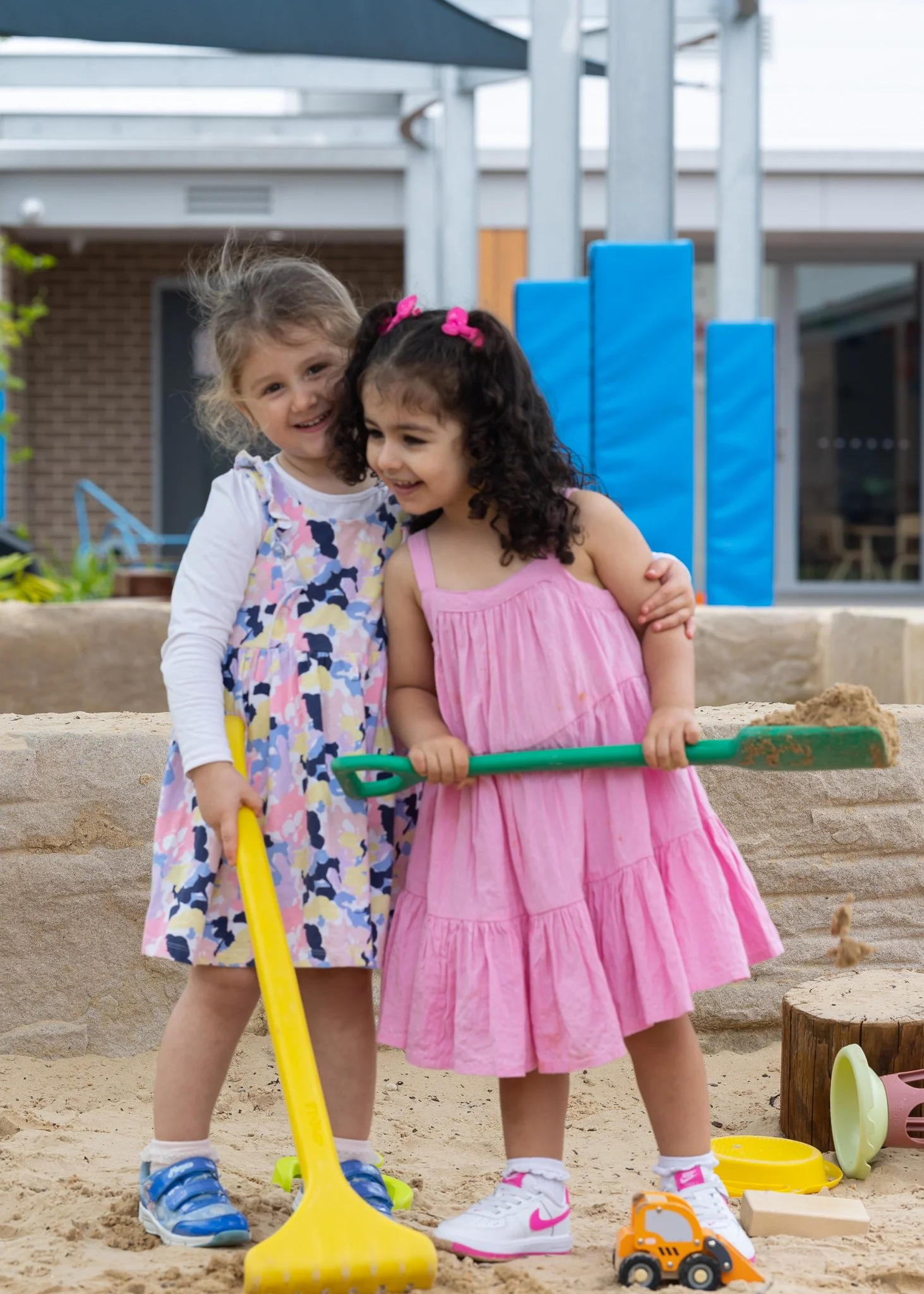 two little girls playing in the sandpit