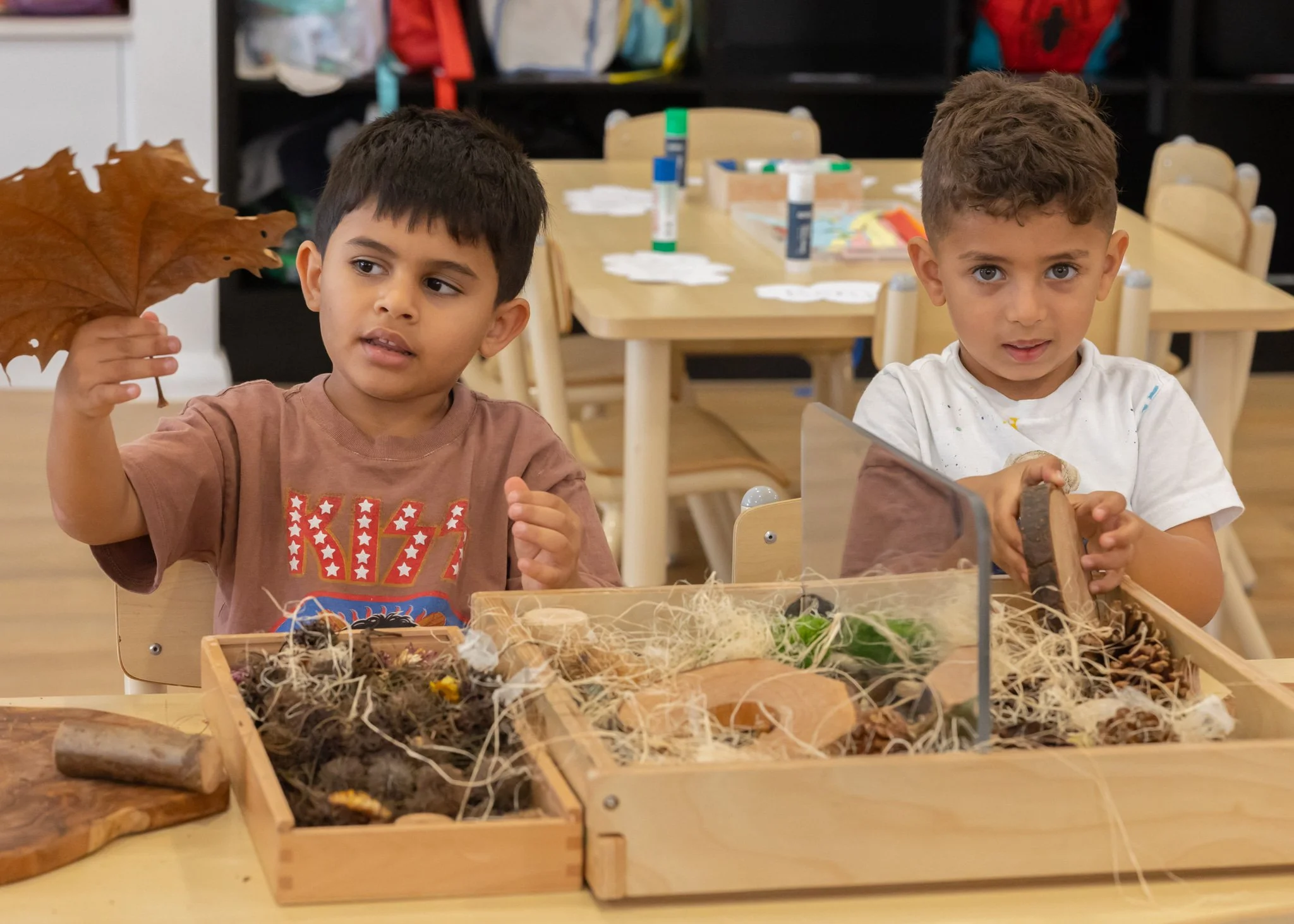 children playing with natural resources including leaves and branches in a classroom