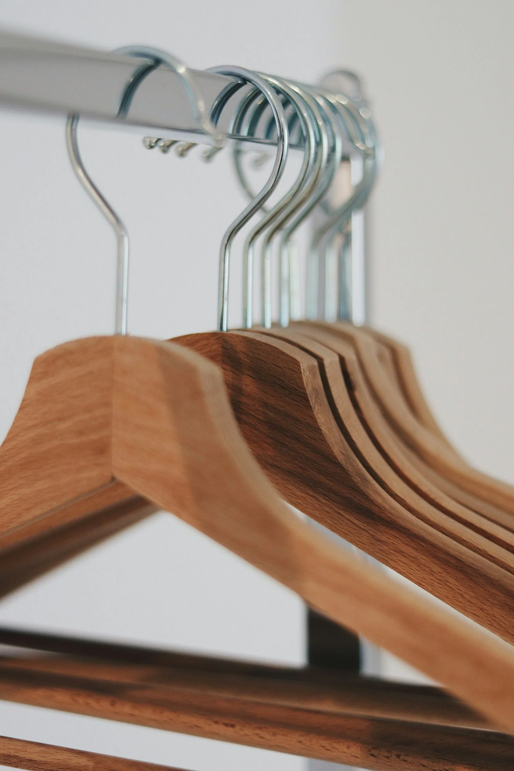 Wooden hangers hanging on a metal clothing rod.