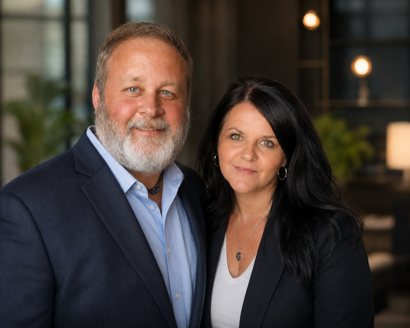 A middle-aged man with a gray beard and a woman with black hair posing together indoors.