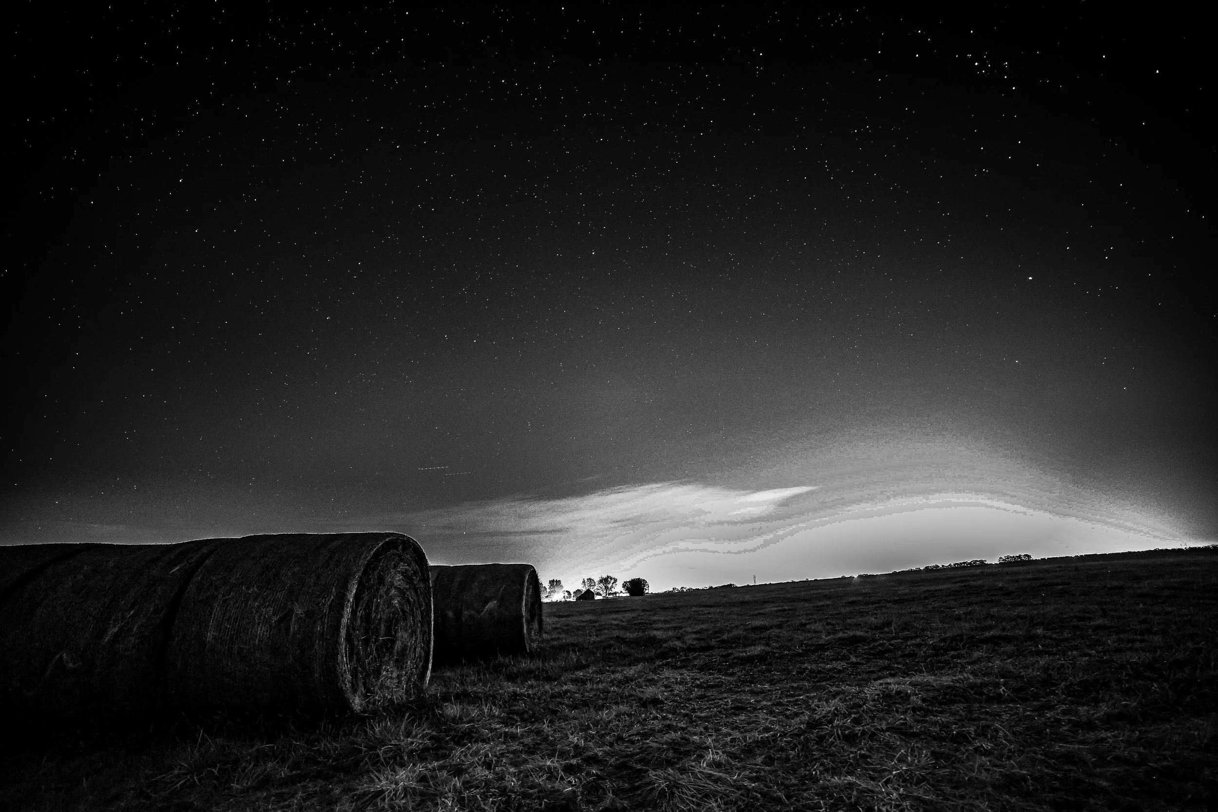 Beneath a sky full of stars, the hay bales rested quietly against the far glow of the horizon.