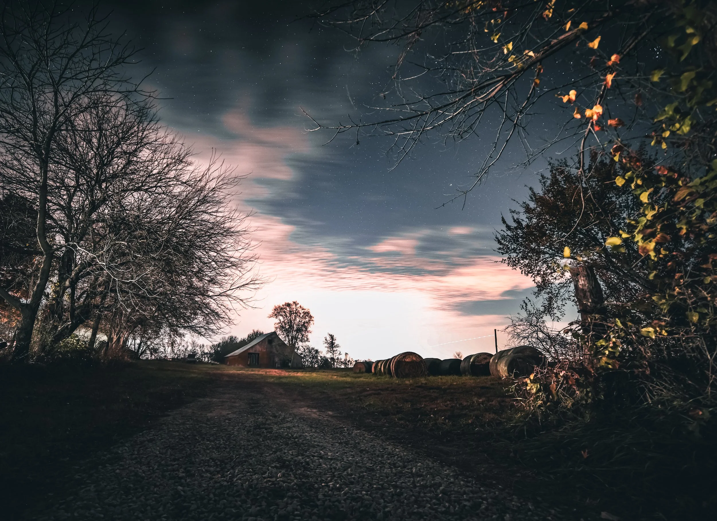 The lane led toward the barn while the night sky stretched wide above the quiet farm.