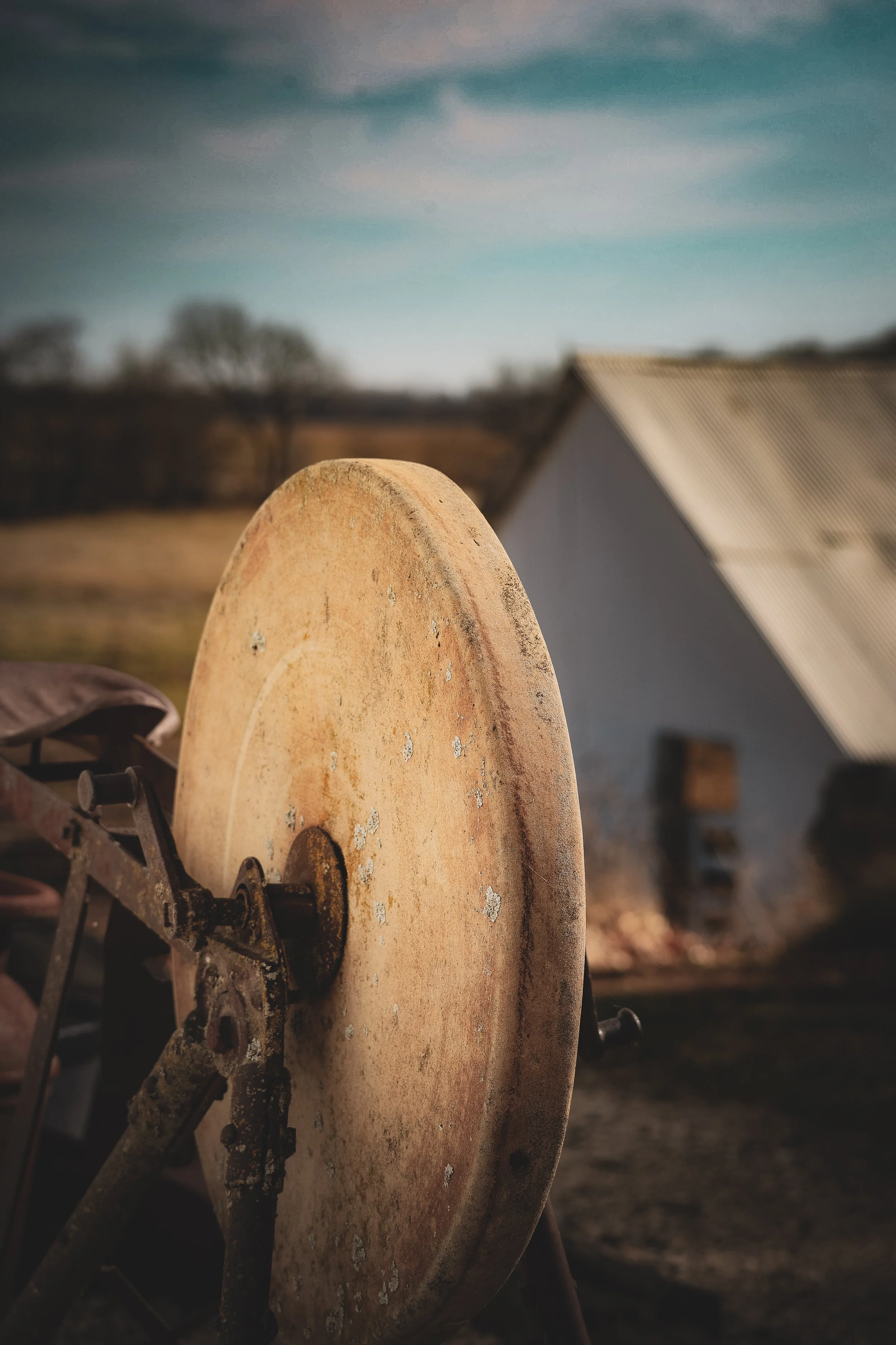 Timeworn and still, this old grindstone carries the quiet labor of another day.