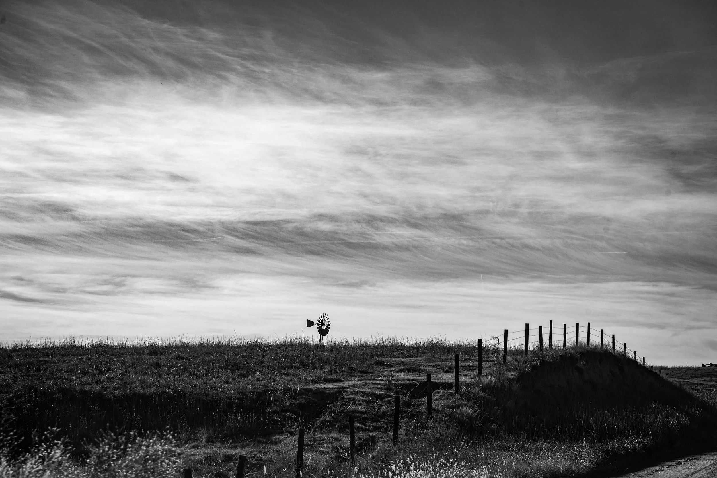 Out in the wide open Kansas prairie, the windmill rises like a small hymn to land, wind, and sky.