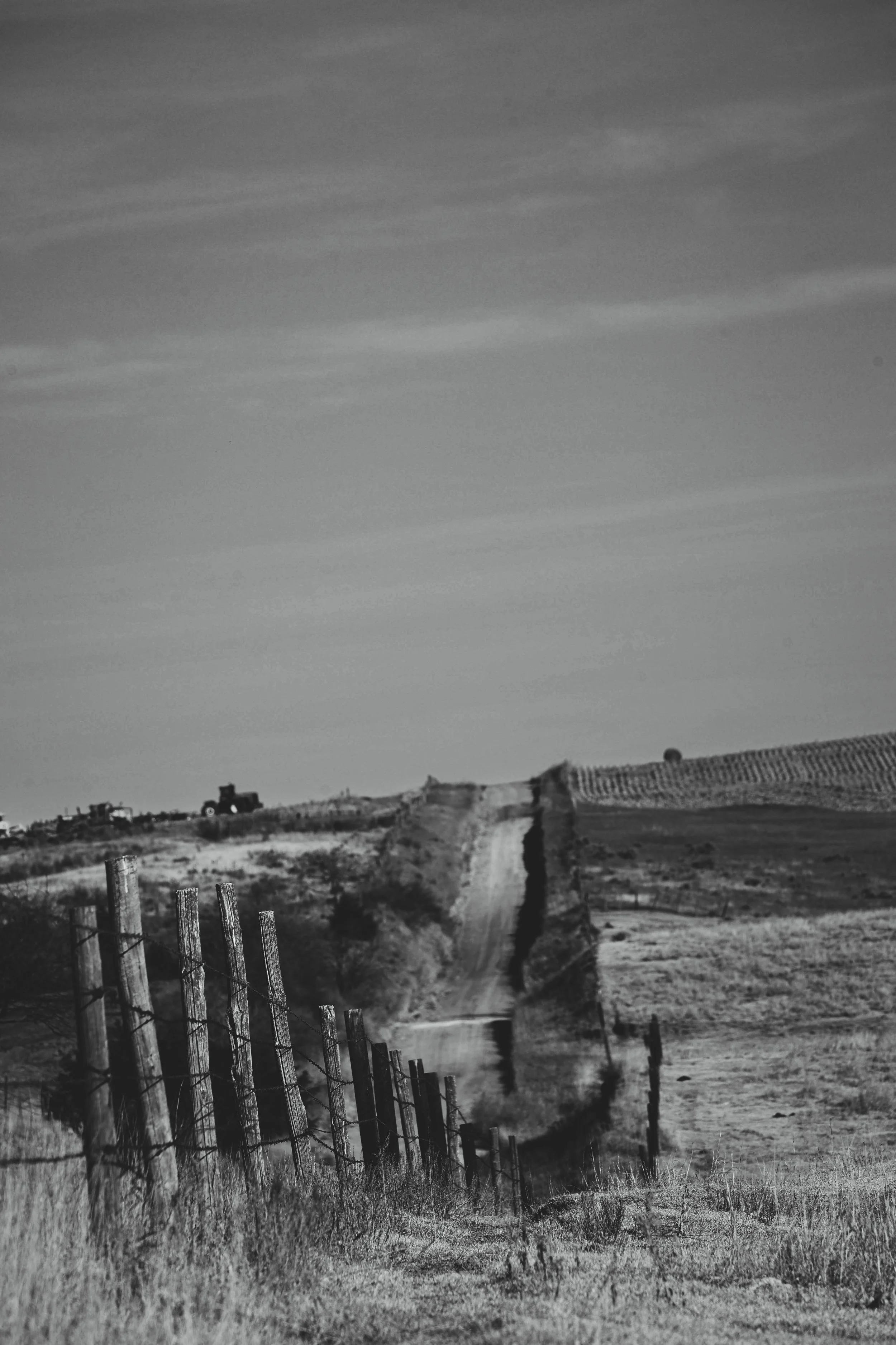 A lonely road and weathered fence line tracing the quiet shape of the land.