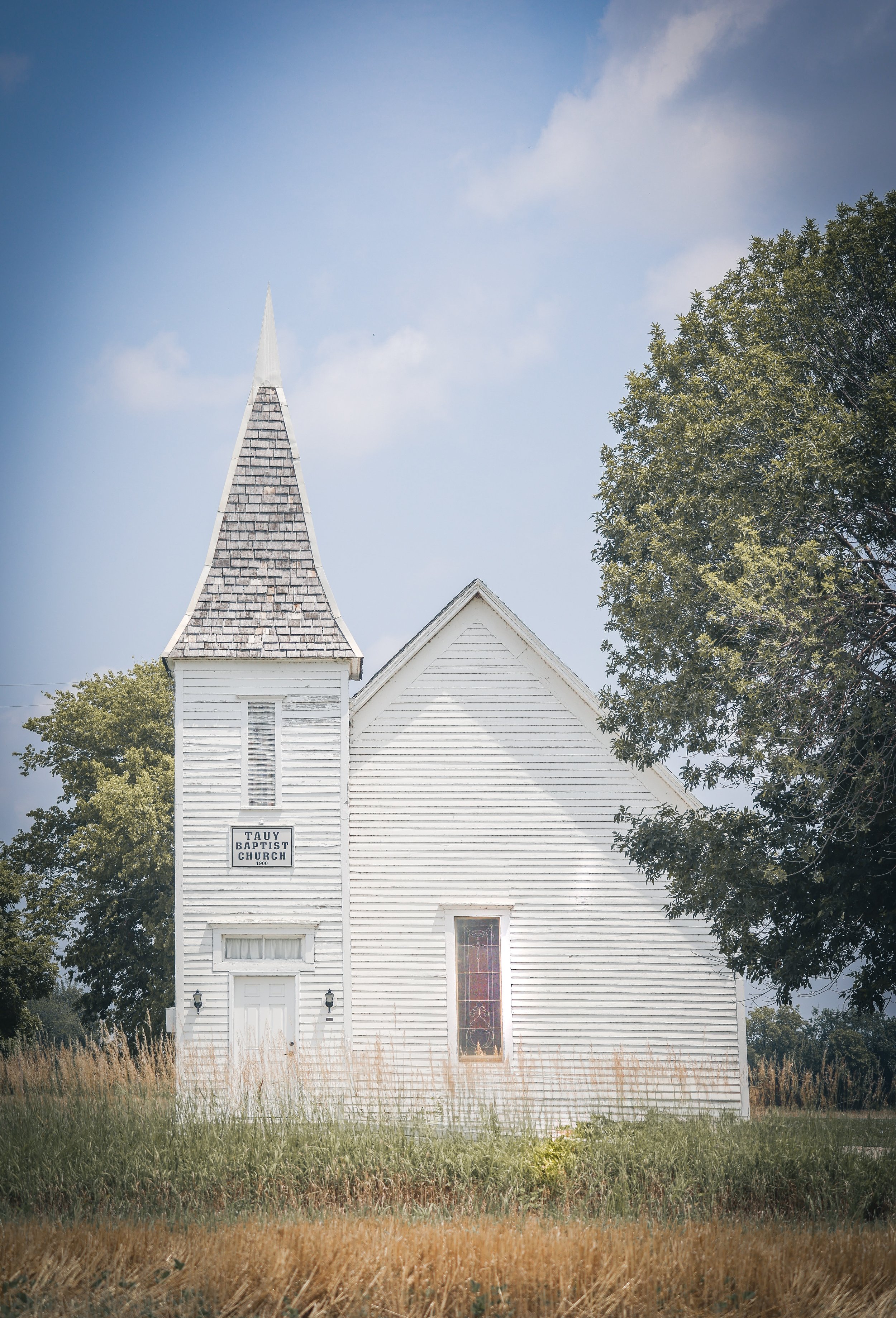 A quiet country church standing with simple grace on the open land.