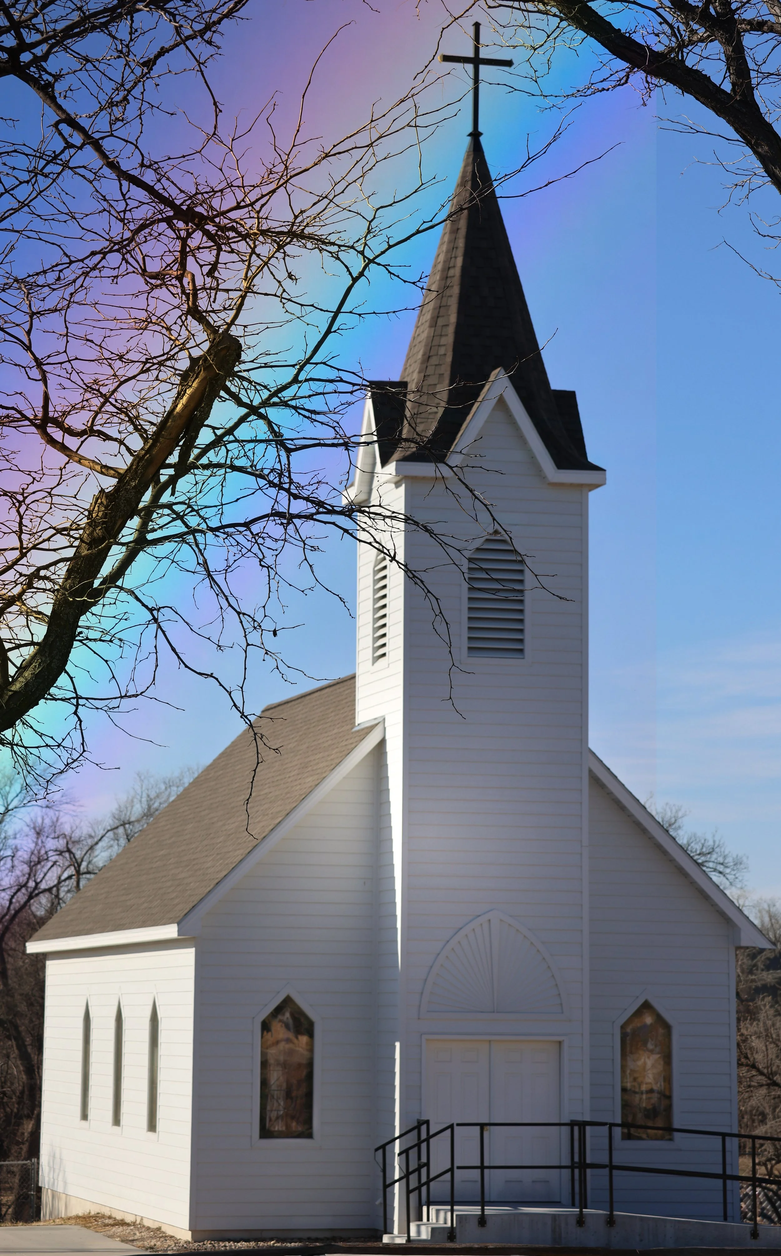 In the stillness of the day, this white church stands like a soft hymn against the sky.