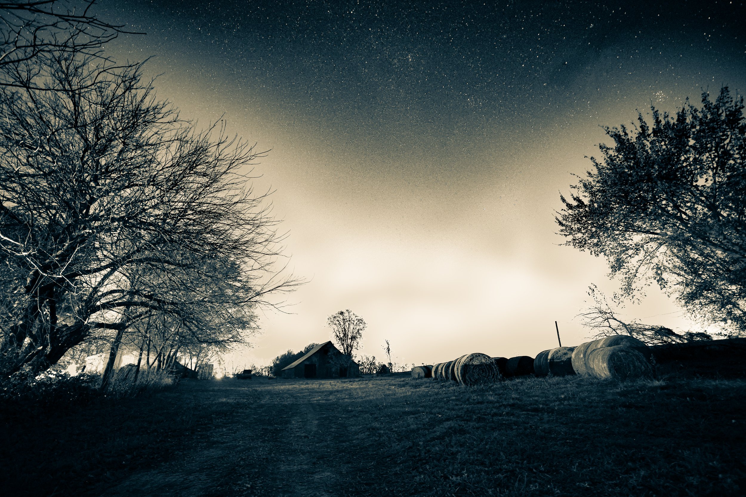 Under a sky full of stars, the barn and hay bales rested in the quiet rhythm of the farm