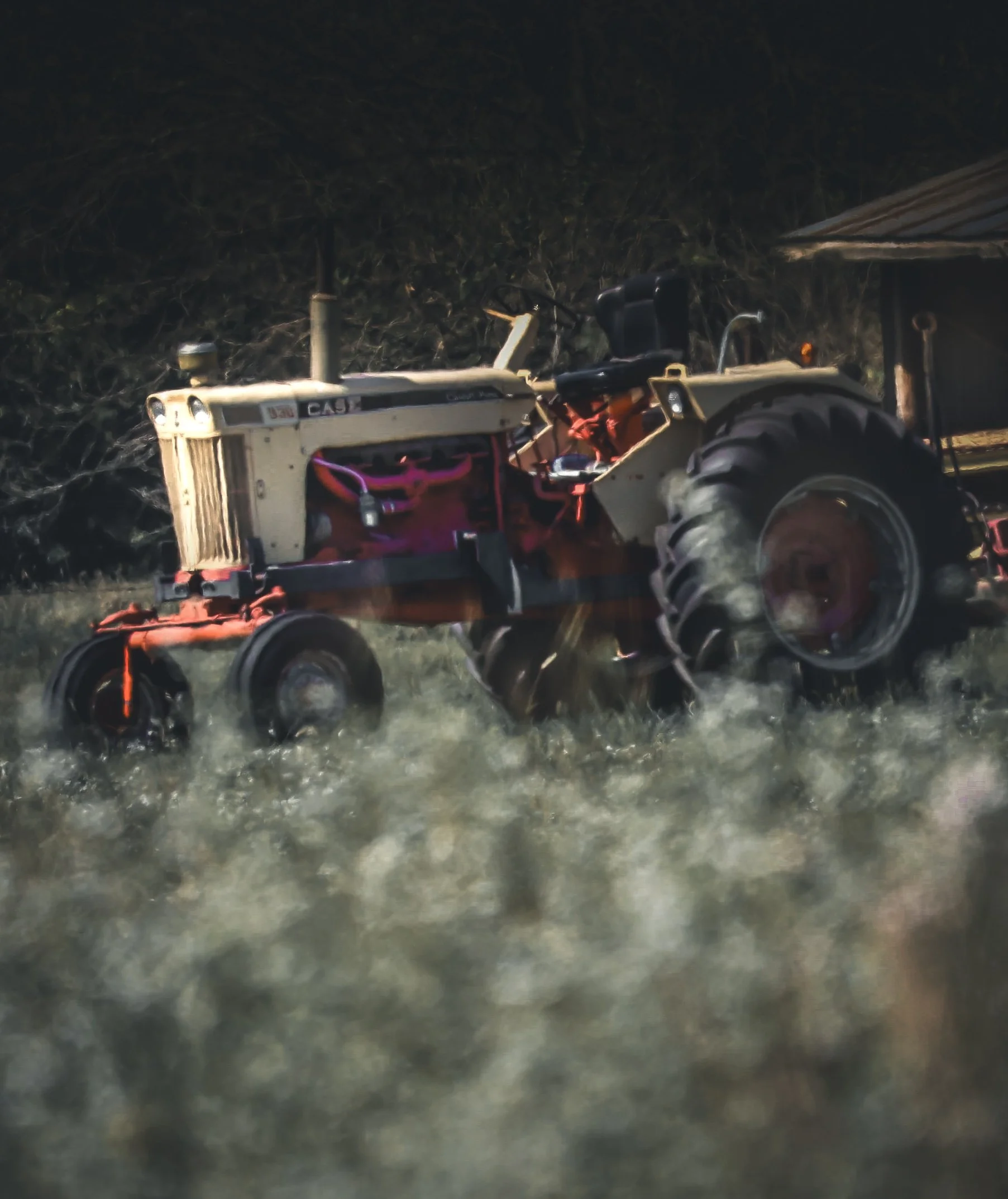 Resting beyond the field, this weathered tractor feels gentle, familiar, and shaped by time.
