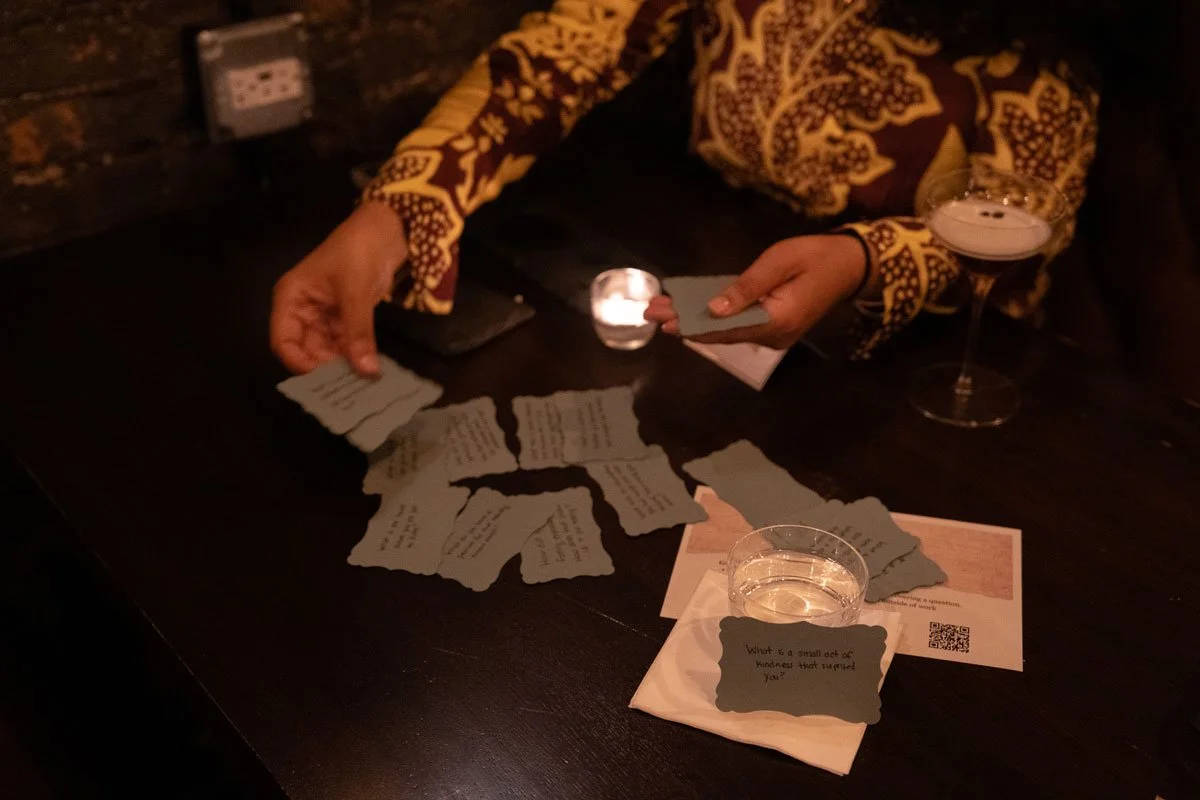 Hands sorting through some hand-written cards on a candle-lit table