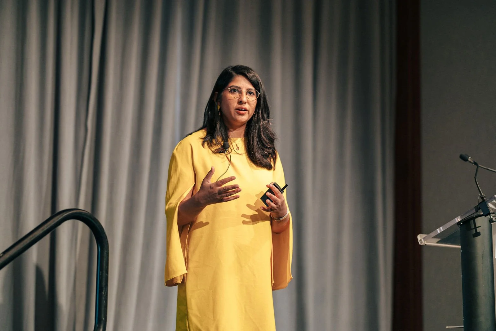 Dr. Payal Beri speaking in a yellow dress on stage