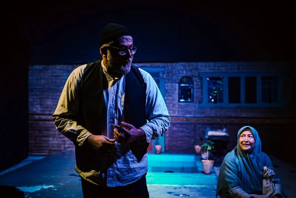 A theatrical scene with a man speaking to a woman with his back to her.