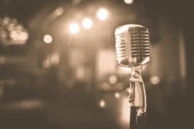 Vintage microphone on stage with blurry background and stage lights.