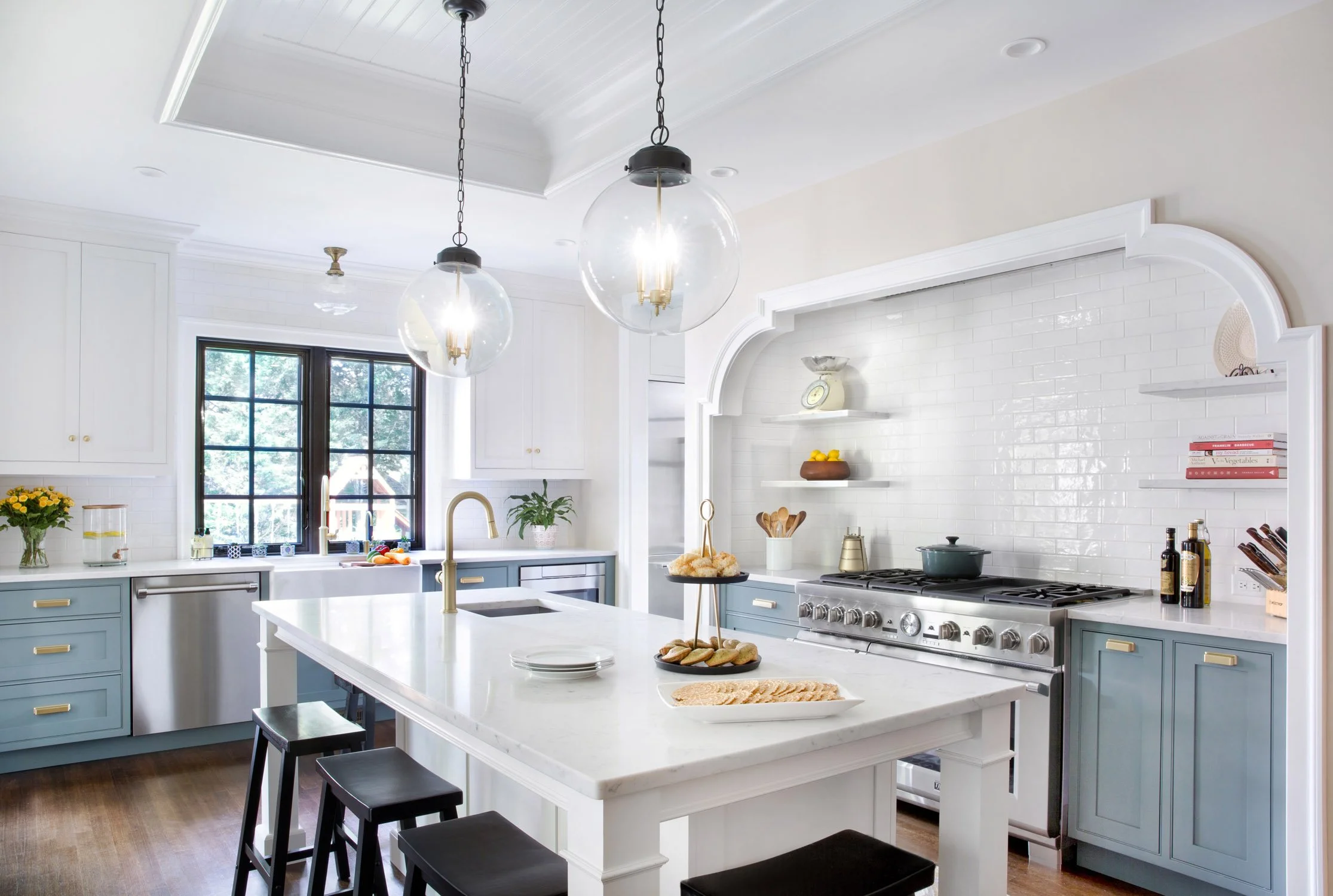 Cadet blue and white painted inset cabinetry, combined with black and brass accents make this simple traditional kitchen a classic. The island with white quartz countertop and 48” range are a chef’s delight.