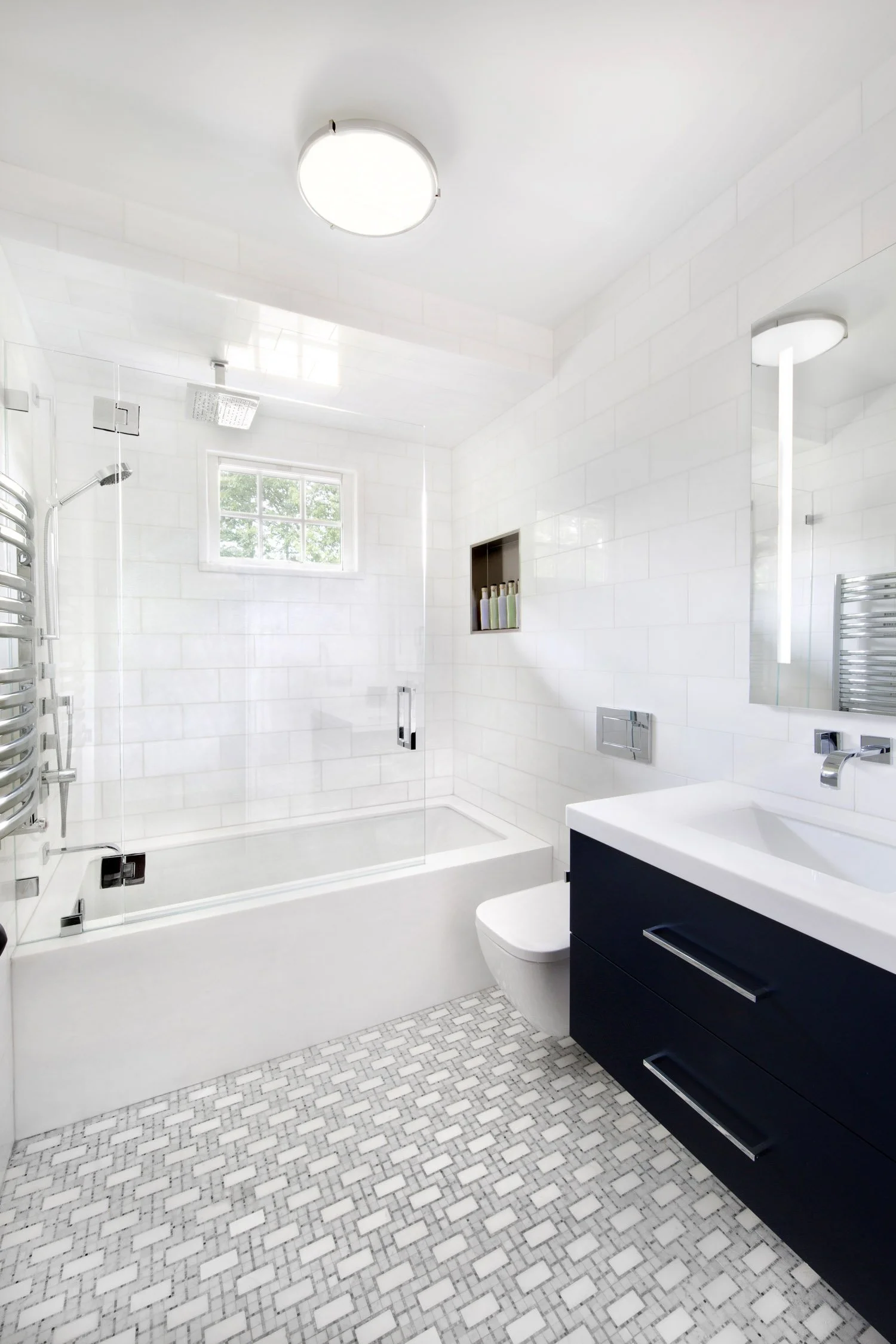 This contemporary full bath is wrapped in thassos marble and glistens in polished chrome. The air tub is surrounded in marble while toilet and vanity float above the marble mosaic floor.